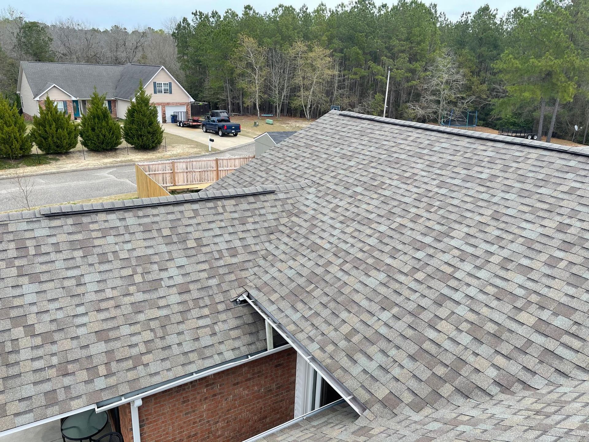An aerial view of a roof of a house with trees in the background.