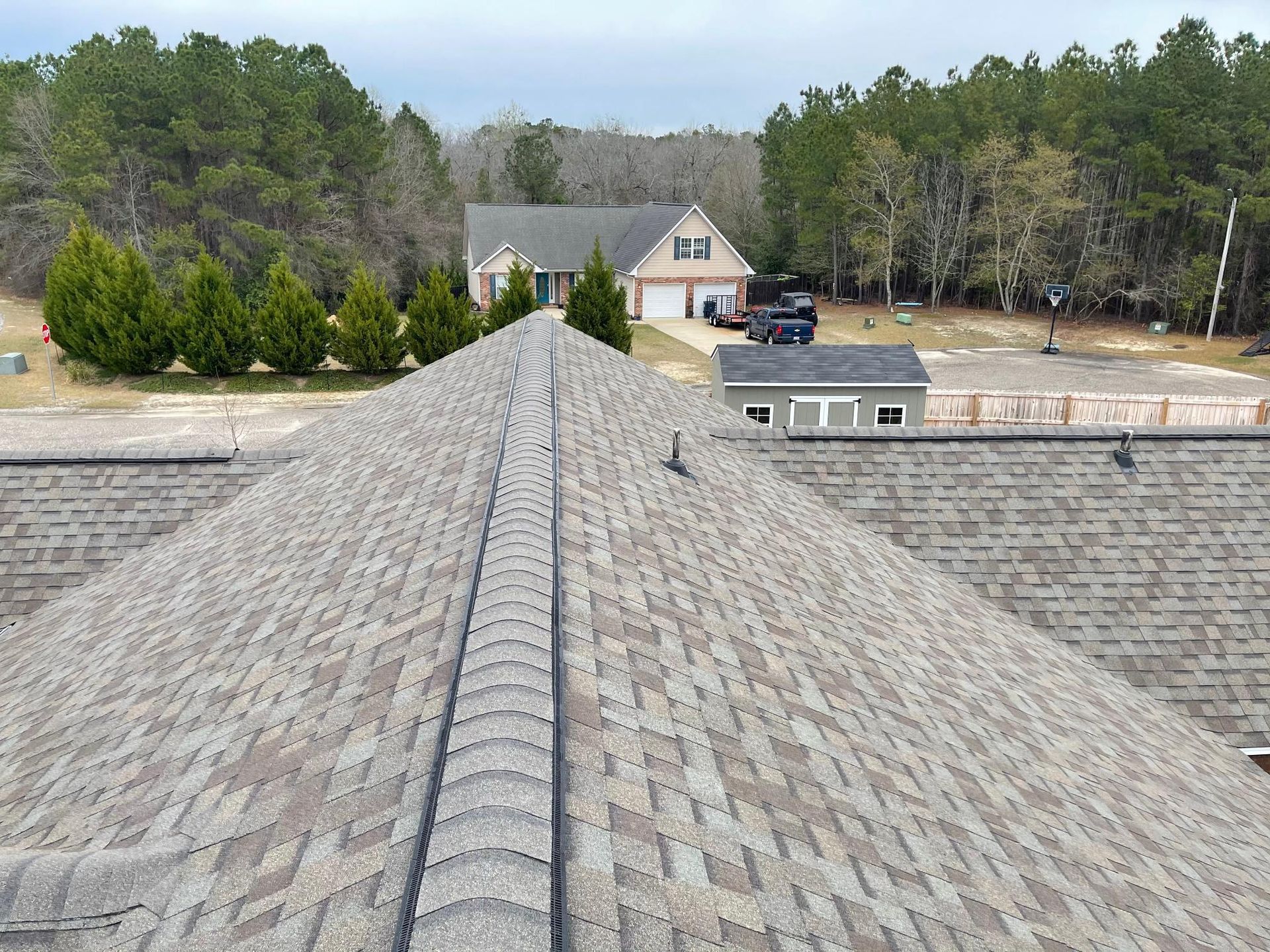 A roof with a house in the background and trees in the foreground
