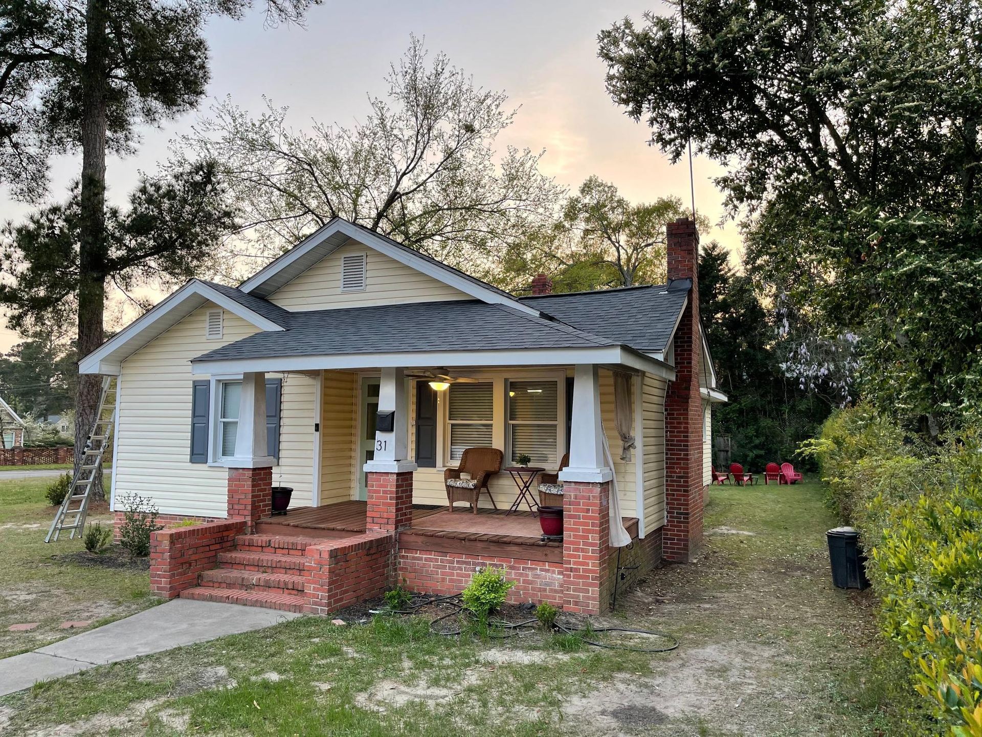 A small white house with a brick porch and a chimney.