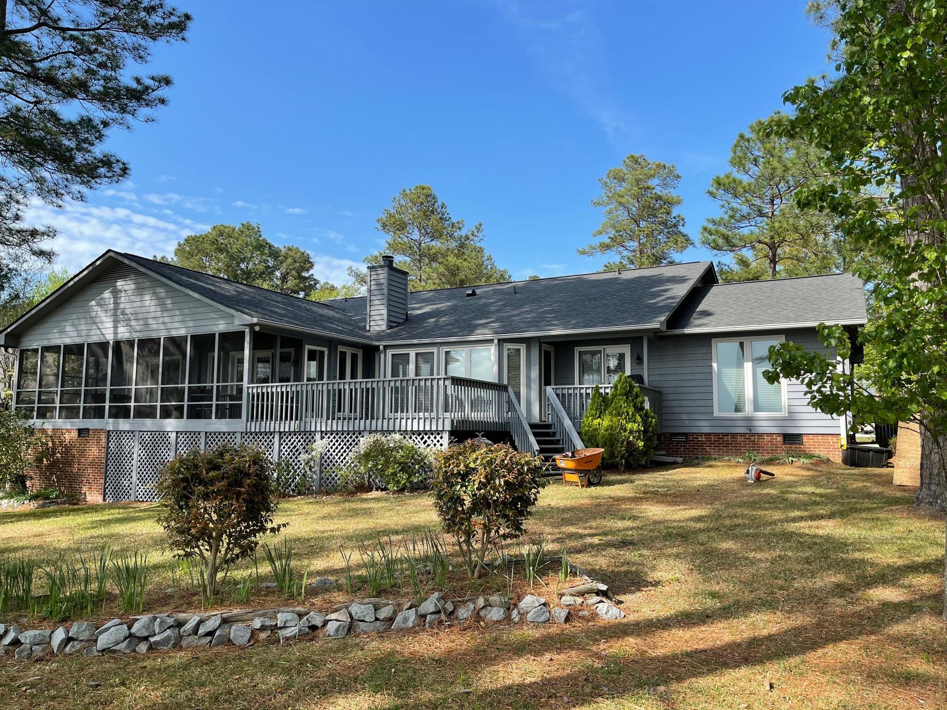 A large house with a screened in porch and a large lawn in front of it.