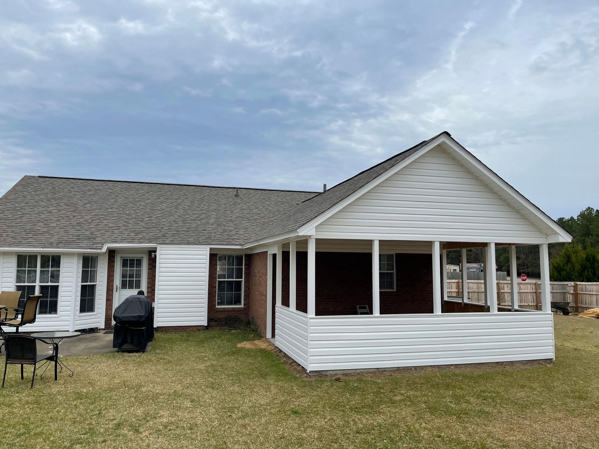 A white house with a screened in porch in the backyard.