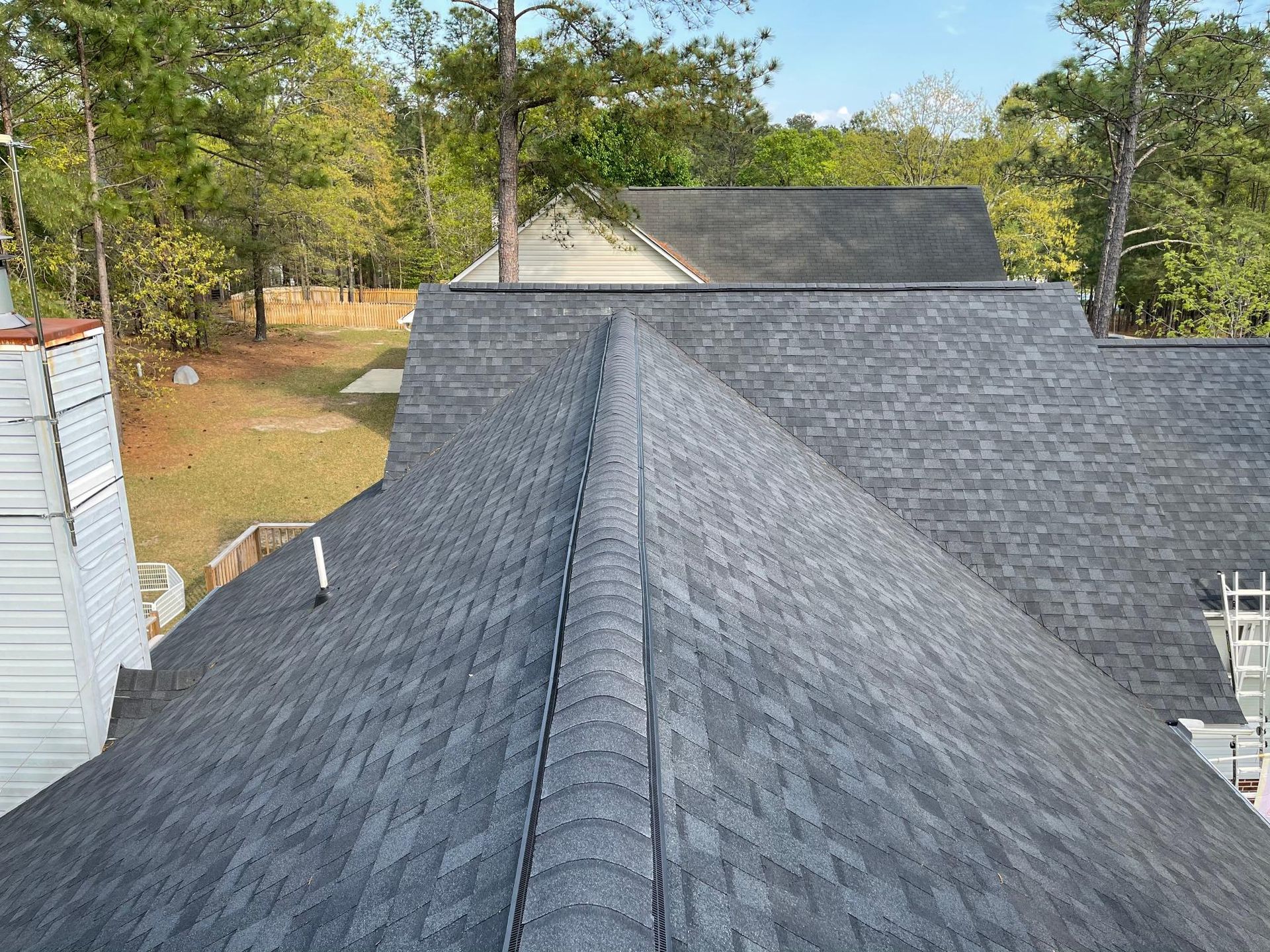 An aerial view of a roof of a house with trees in the background.