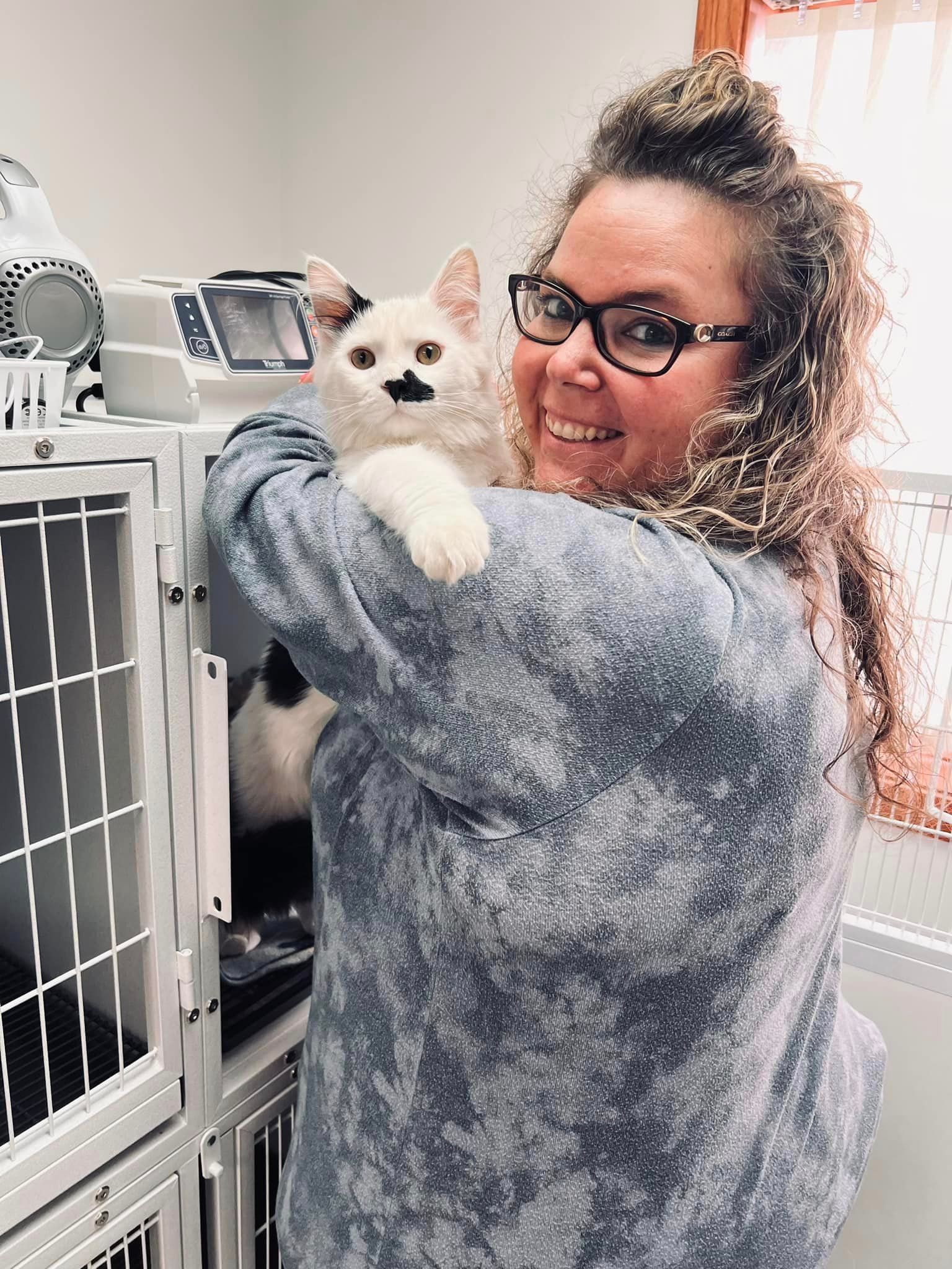 A woman is holding a white cat in her arms.