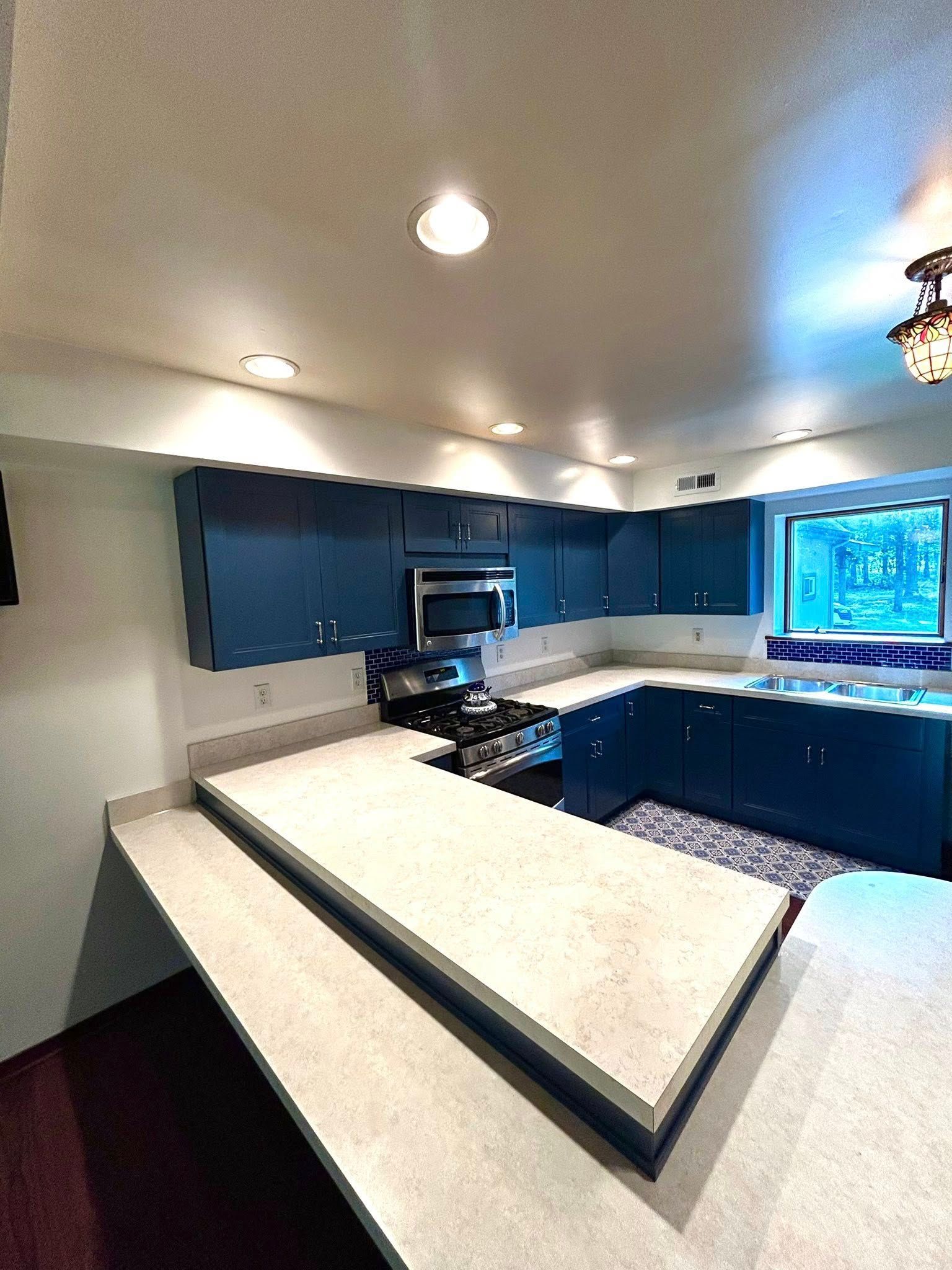 Blue kitchen cabinets with light countertops and a gas range.