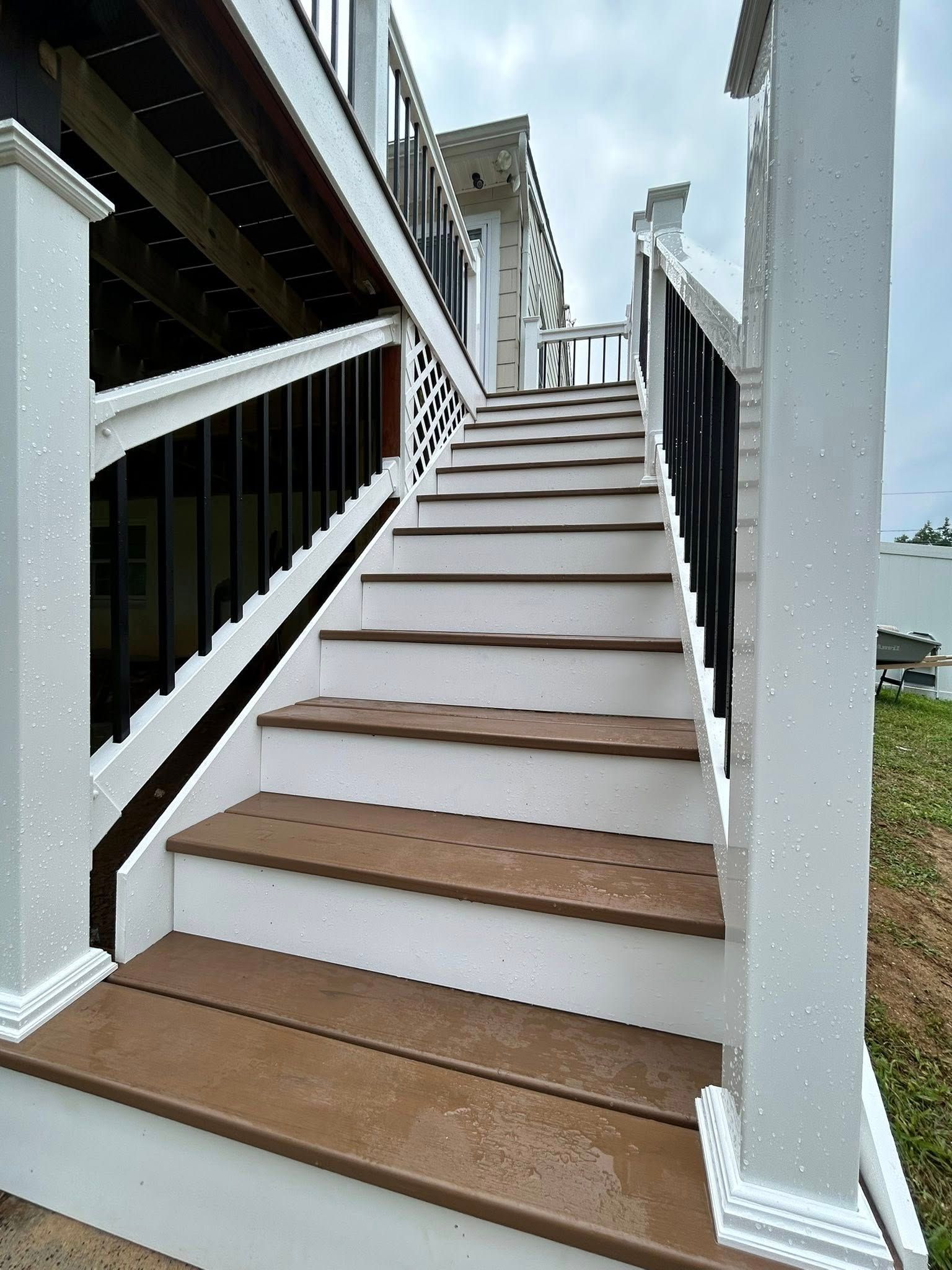 Exterior staircase with white framing, brown steps, black railings.