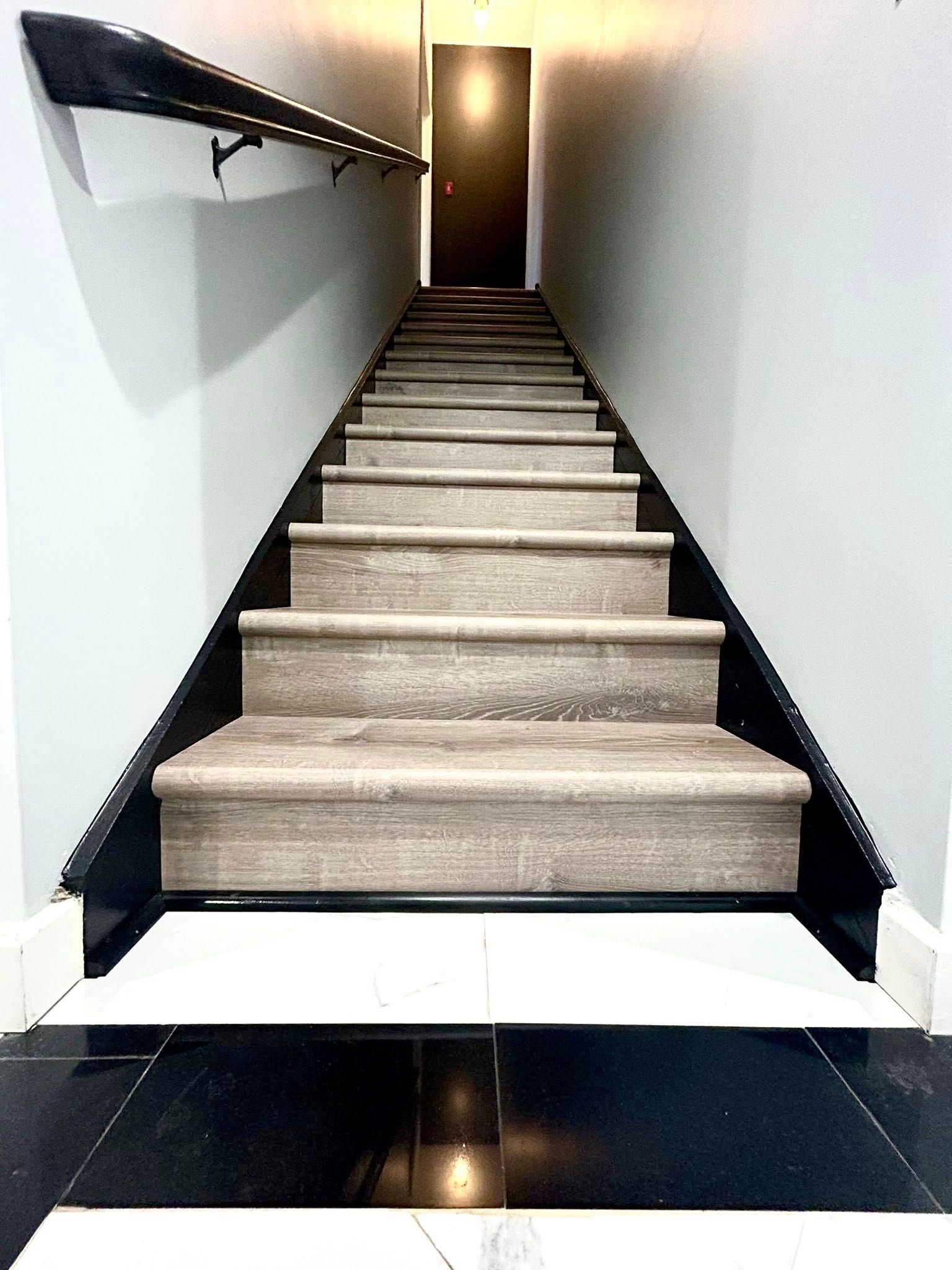 Staircase with gray carpeted steps, black trim, and a door at the top.