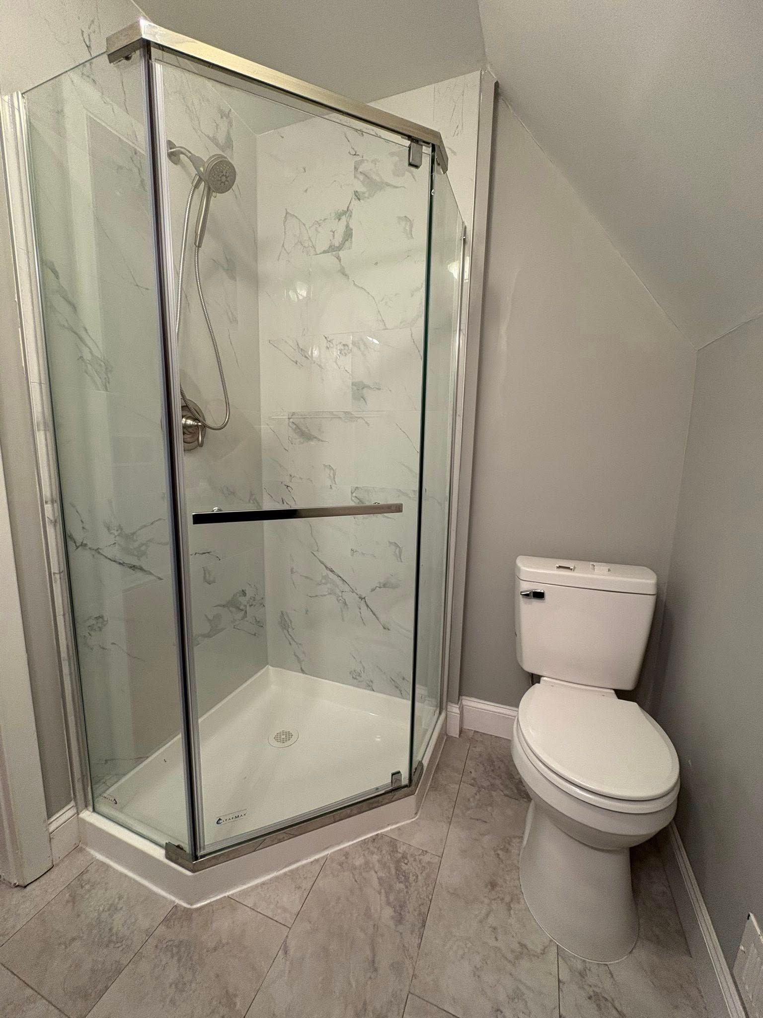 Modern bathroom with a glass shower enclosure and a white toilet. 