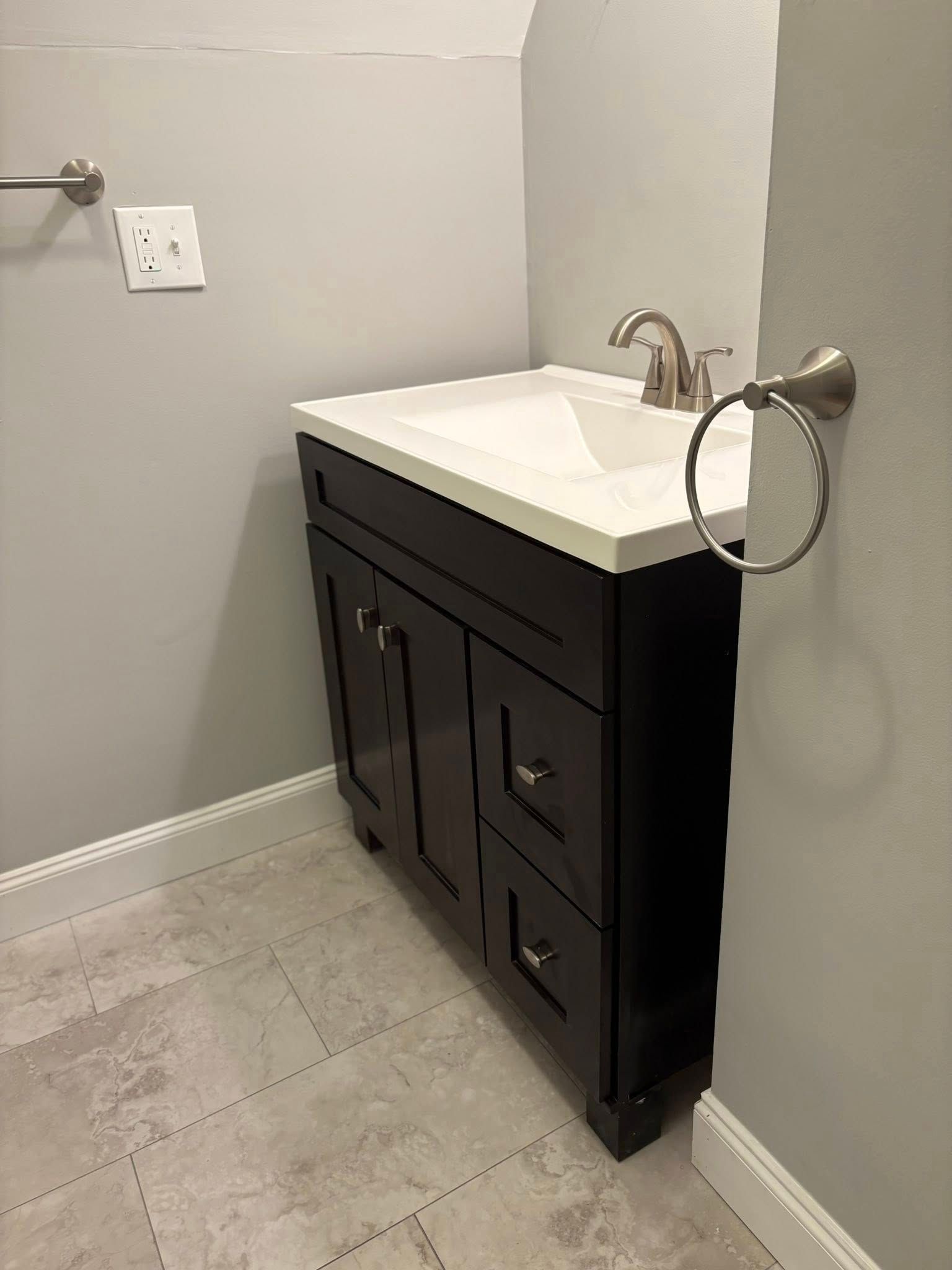 Bathroom vanity with dark brown cabinet, and tile floor.