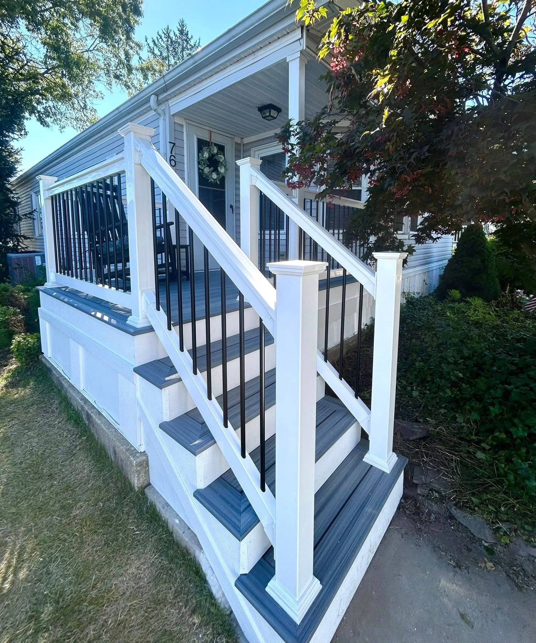 White and gray house with porch and black metal railings.