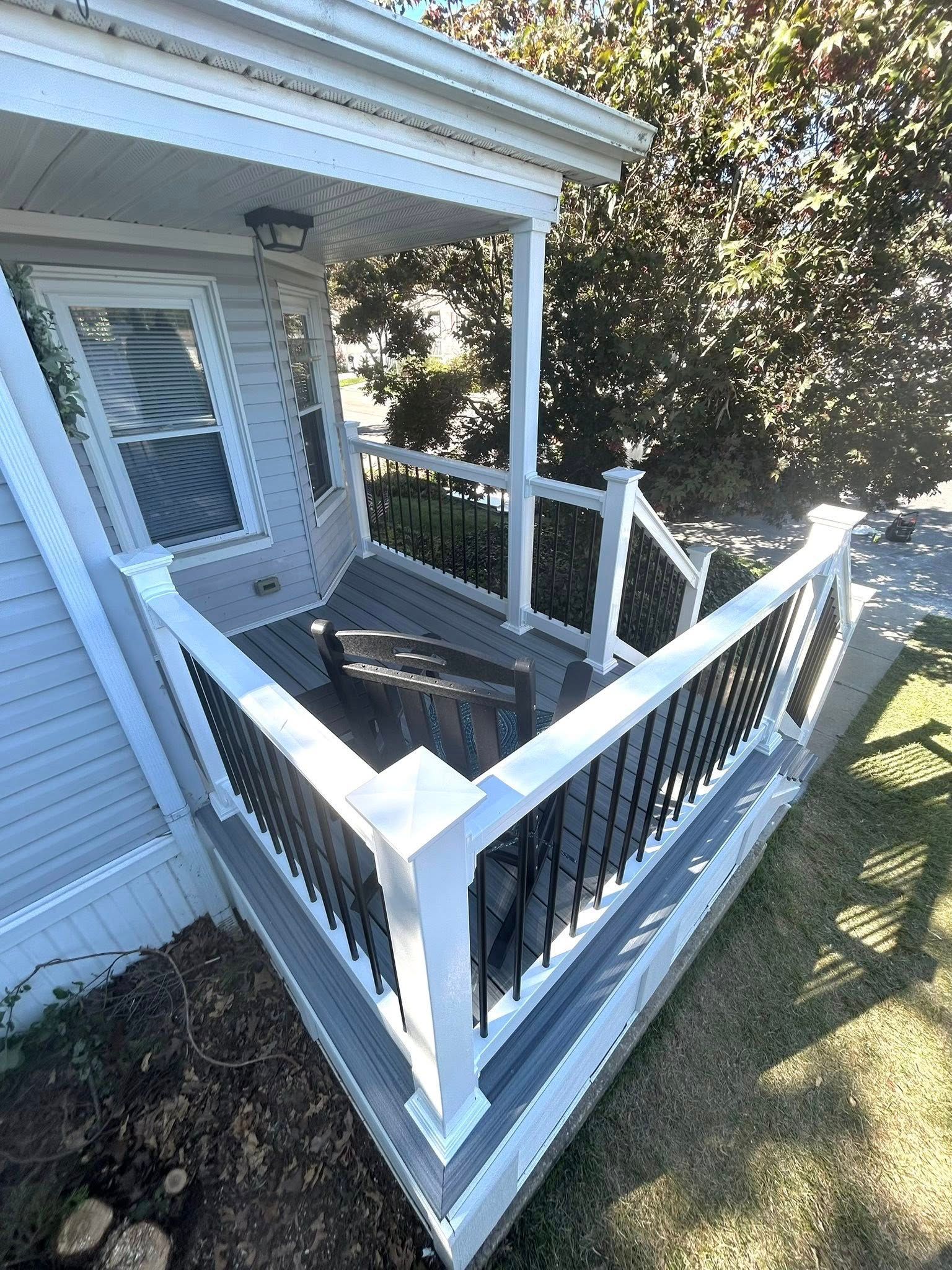 Gray porch with white trim, black railings, and a small bench.