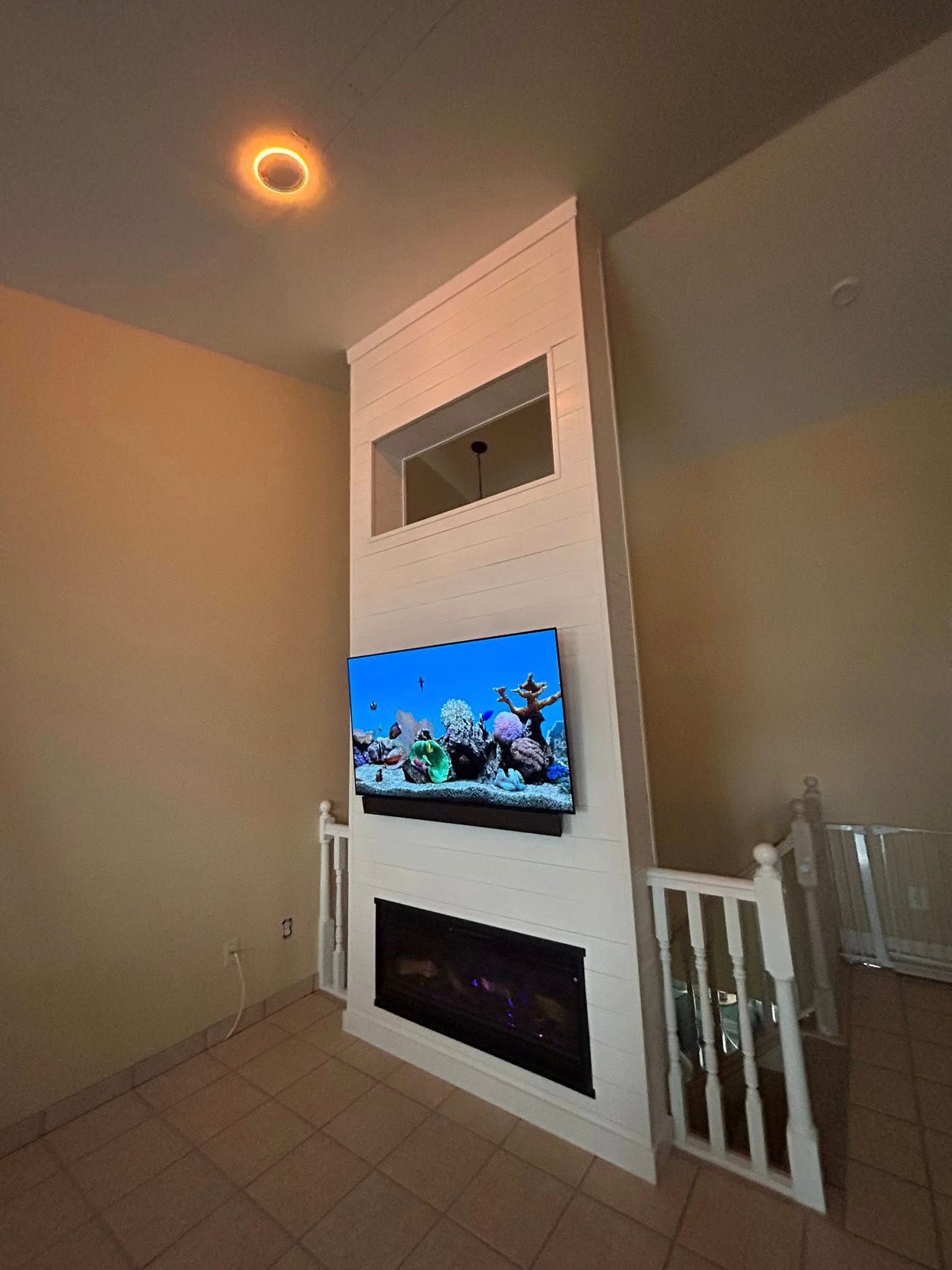 Living room with a wall-mounted TV, fireplace, and railing.