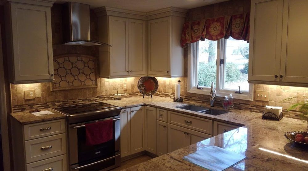 A kitchen with white cabinets , granite counter tops , stainless steel appliances and a window.