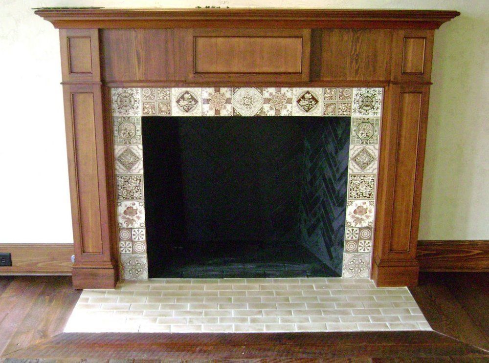 A fireplace with a wooden mantle and tiles around it