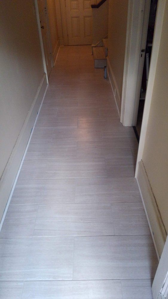 A hallway with a white wooden floor and a staircase.