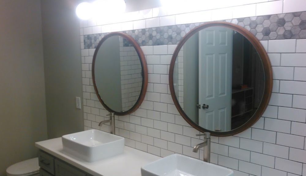 A bathroom with two sinks and two round mirrors.