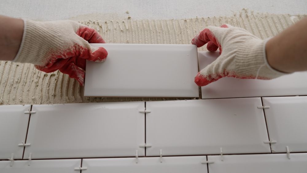 A person is laying tiles on a wall.