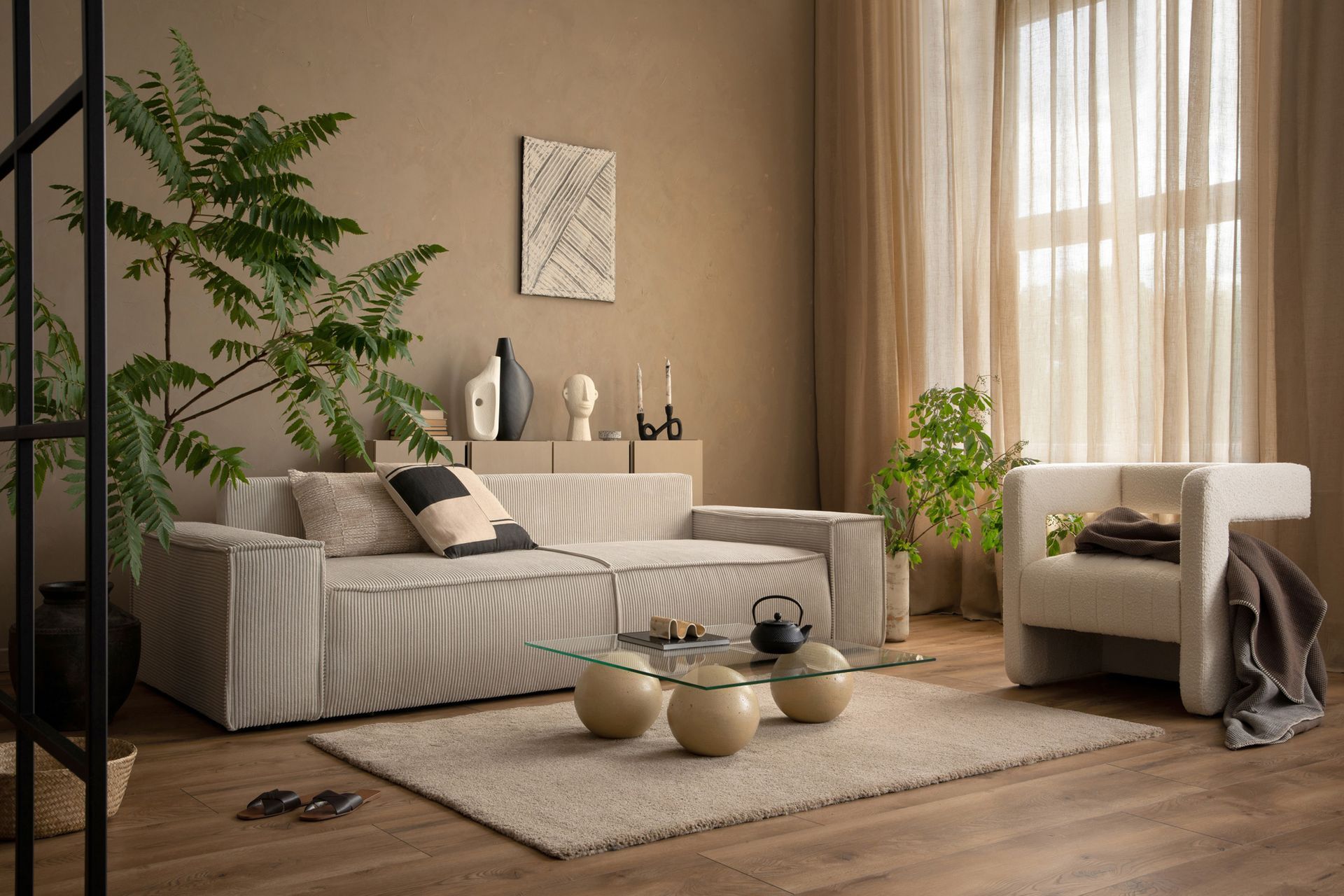 A living room with a couch, chair, coffee table and plants.