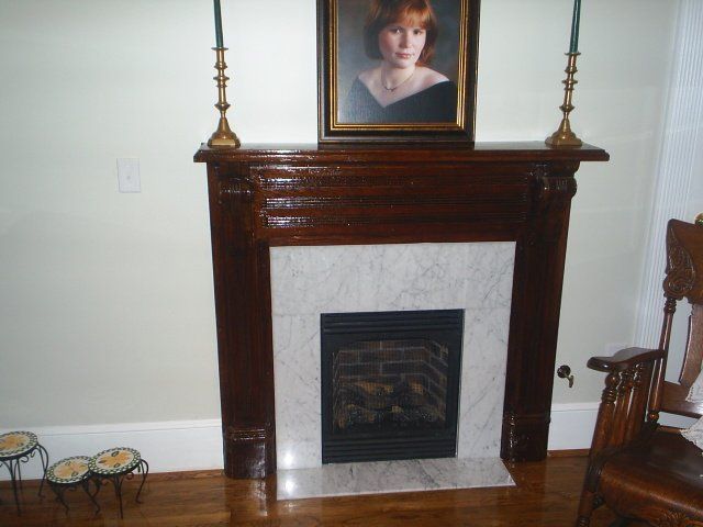 A fireplace with a picture of a woman above it.