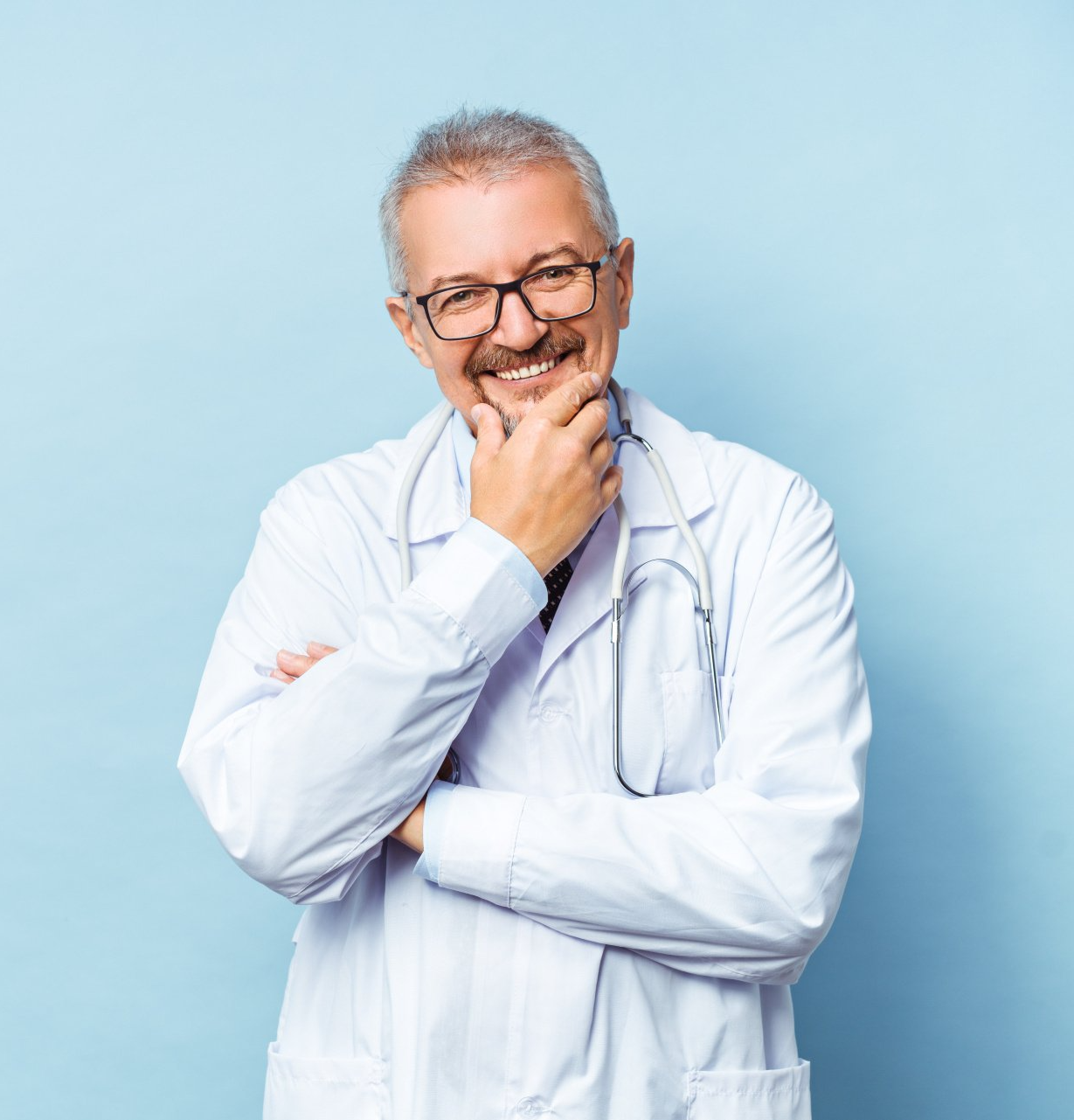 A doctor with a stethoscope around his neck is smiling with his hand on his chin.