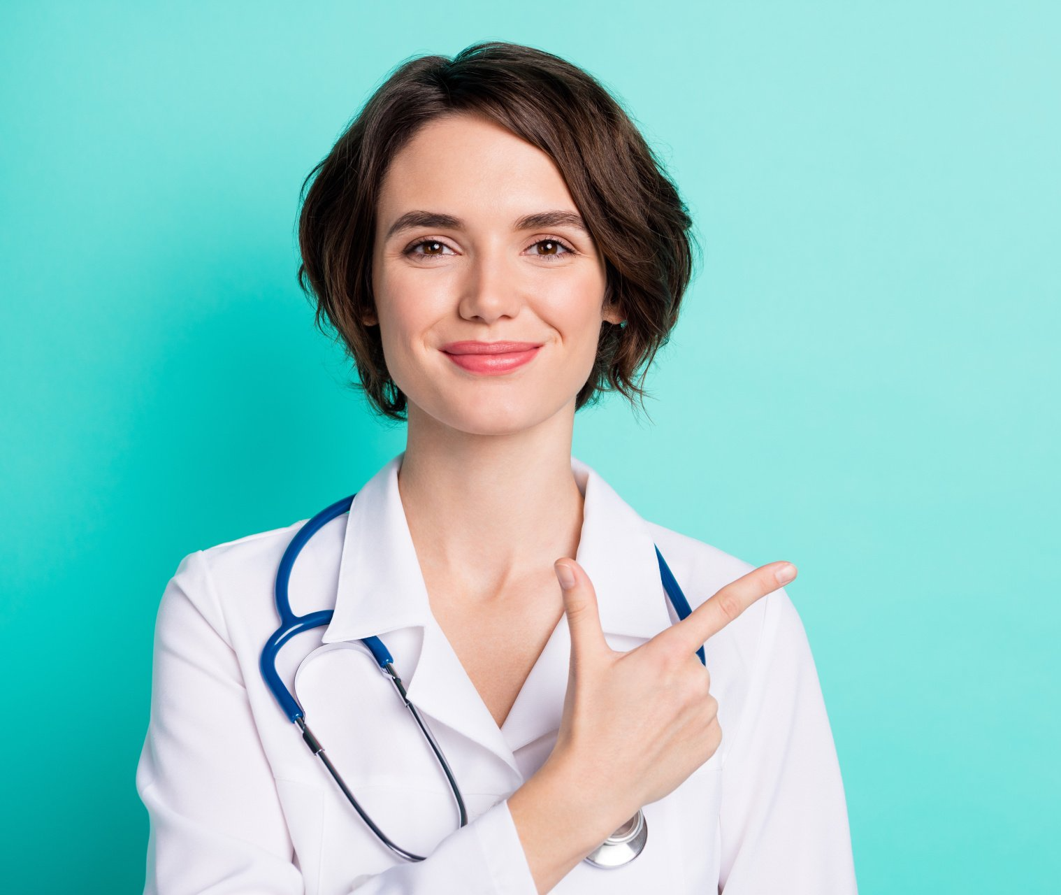 A female doctor with a stethoscope around her neck is pointing to the side.