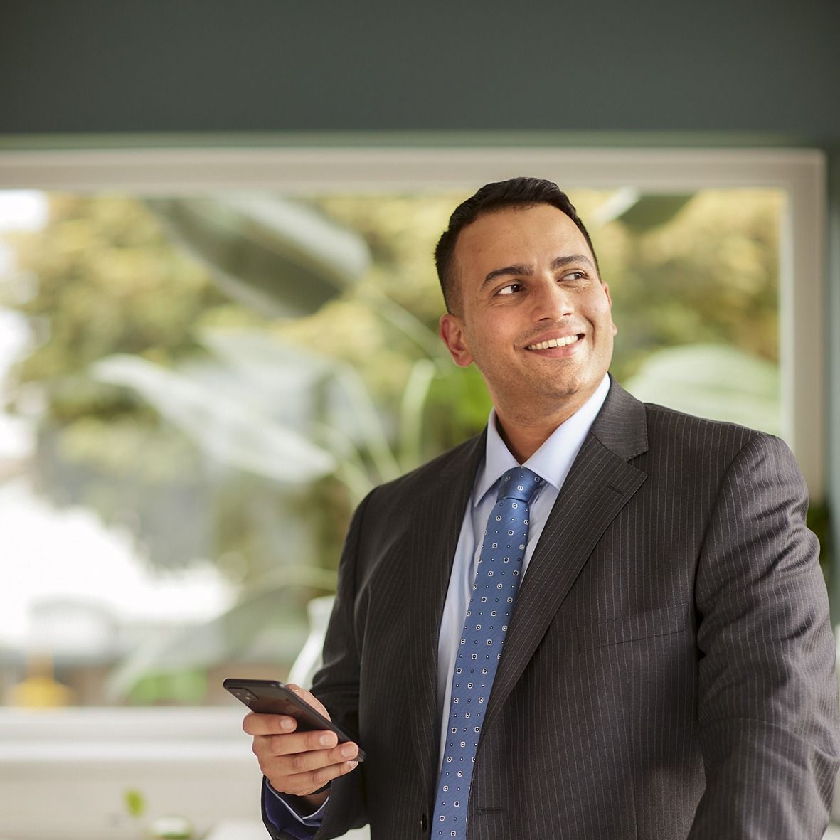 A man in a suit and tie is holding a cell phone