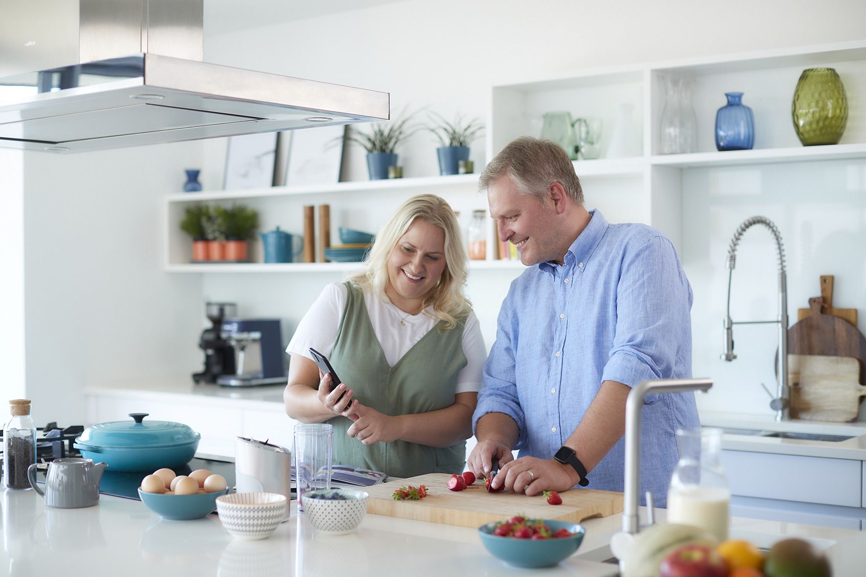 A man and a woman are standing in a kitchen preparing food.