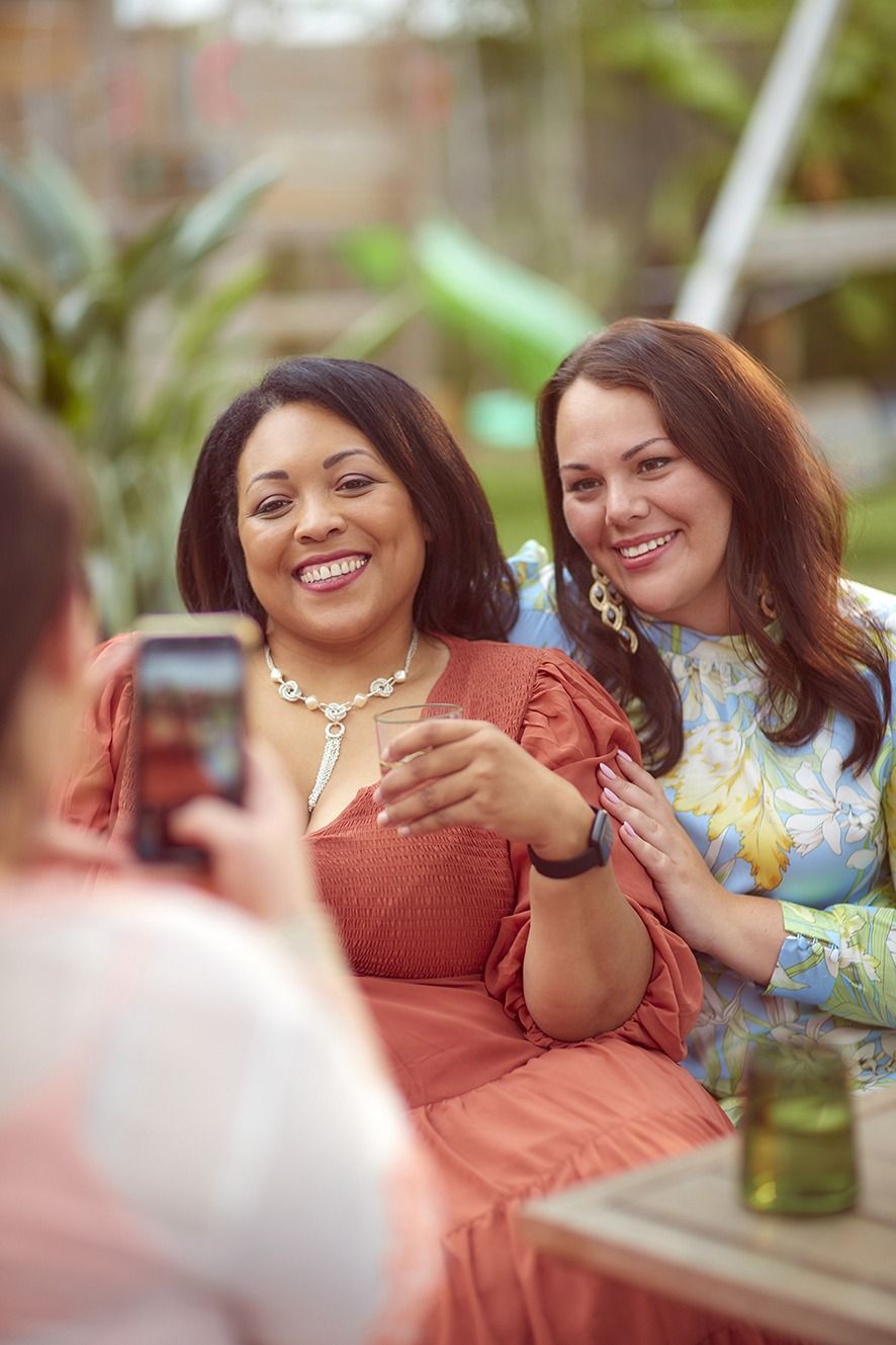 A woman is taking a picture of two women sitting at a table.