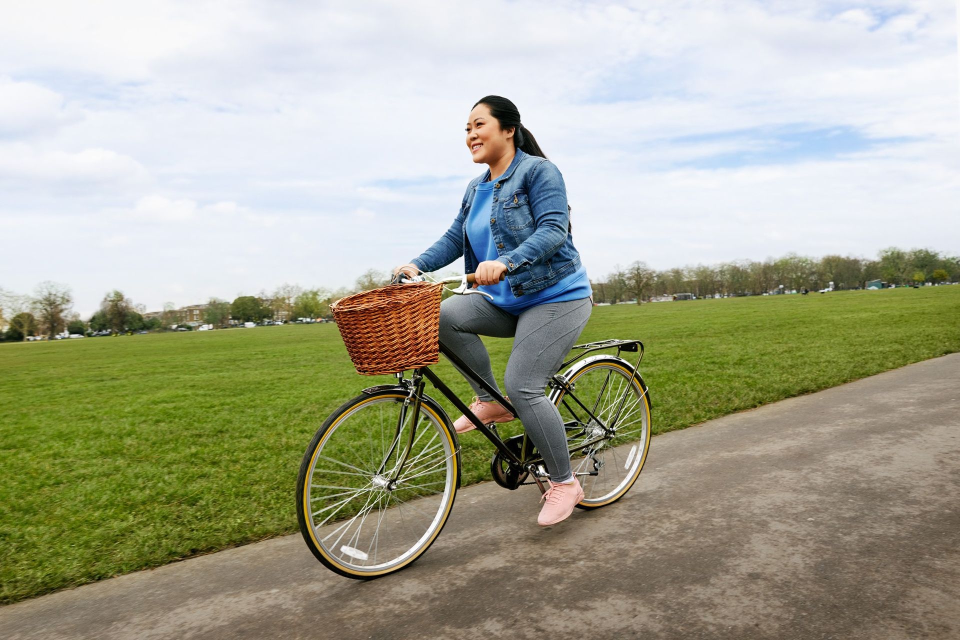 A woman is riding a bike on a path in a park.