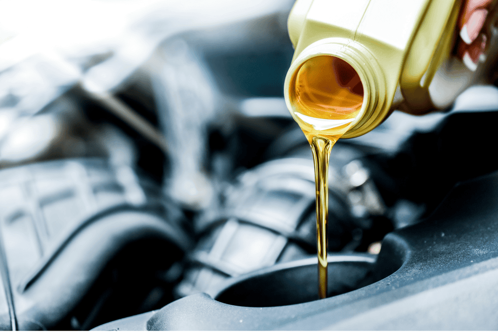 Pouring motor oil into a car engine; gold liquid, close-up.