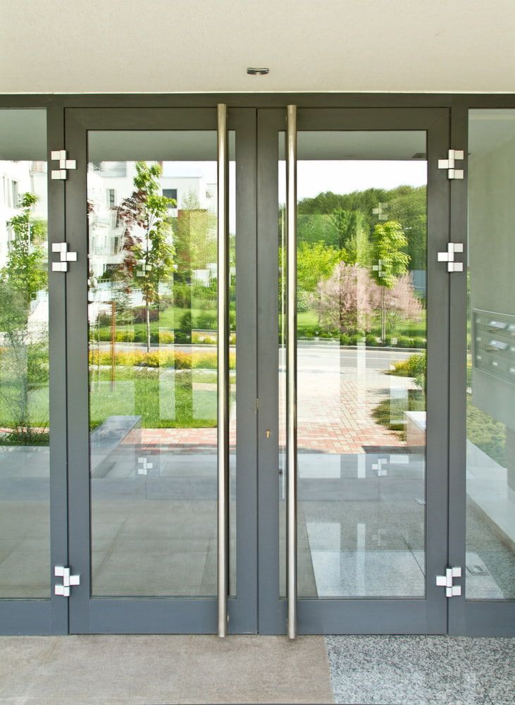 A Pair Of Glass Doors With A Stainless Steel Handle — Hayes & Swinburn Glass in Westcourt, QLD