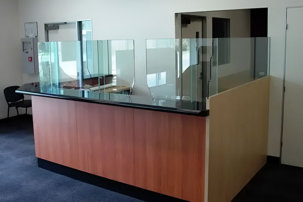 A Wooden Counter With A Glass Divider In A Room — Hayes & Swinburn Glass in Westcourt, QLD