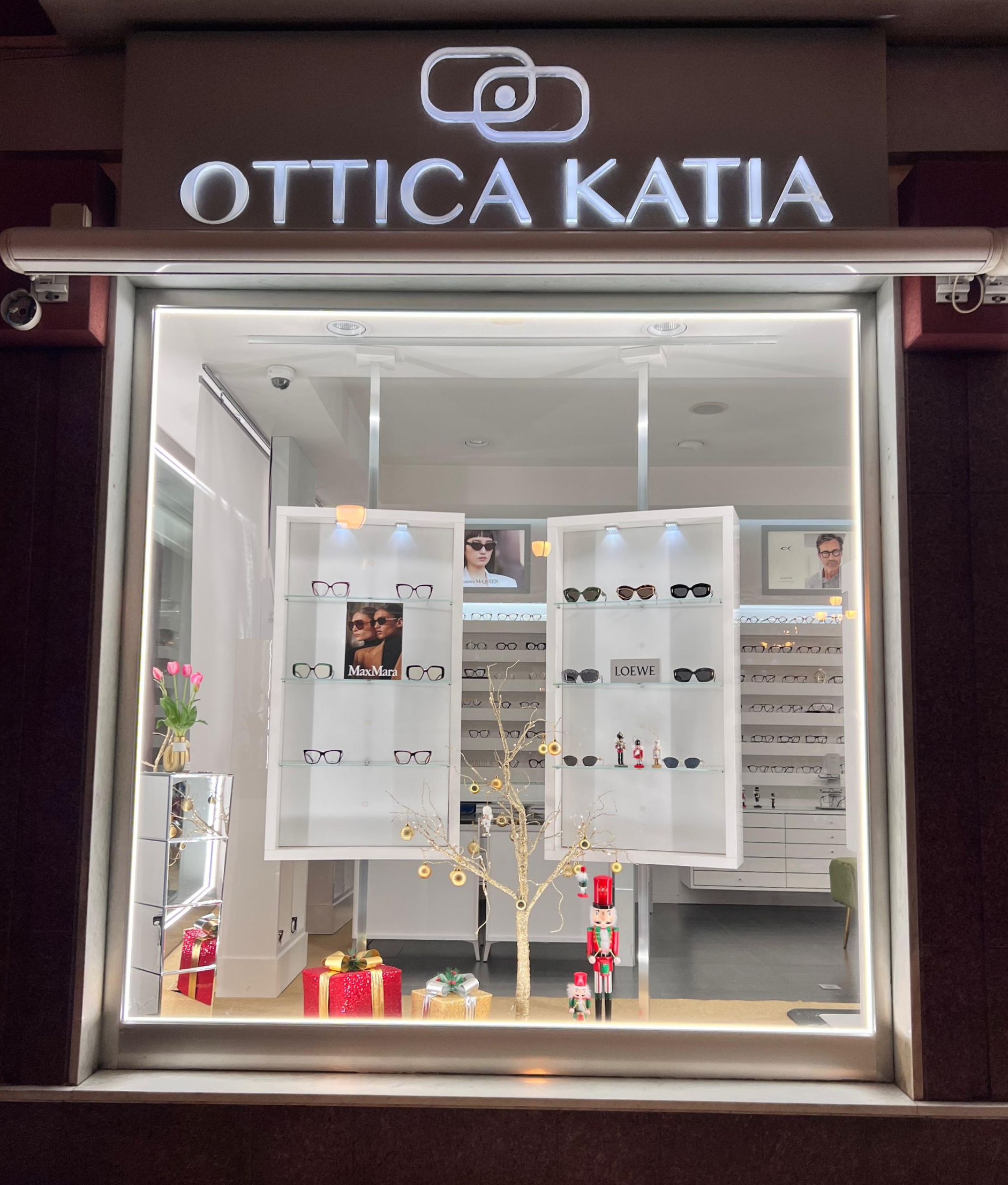 Vetrina di un ottico con occhiali. Insegna luminosa con la scritta 