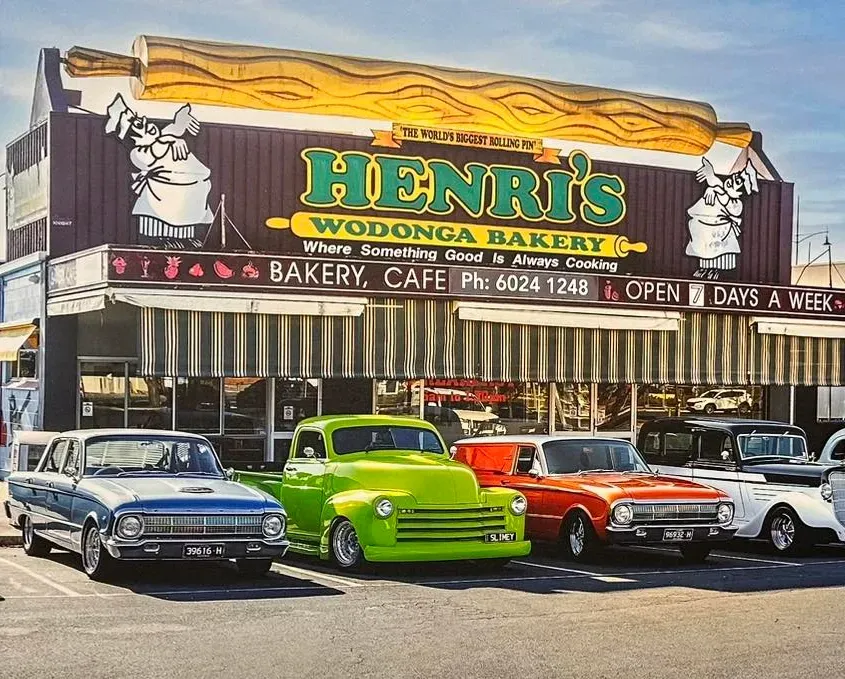 Vintage Cars Parked Outside Henri's With Worlds Largest Rolling Pin on the Roof — Henri's Wodonga Bakery in Wodonga, VIC