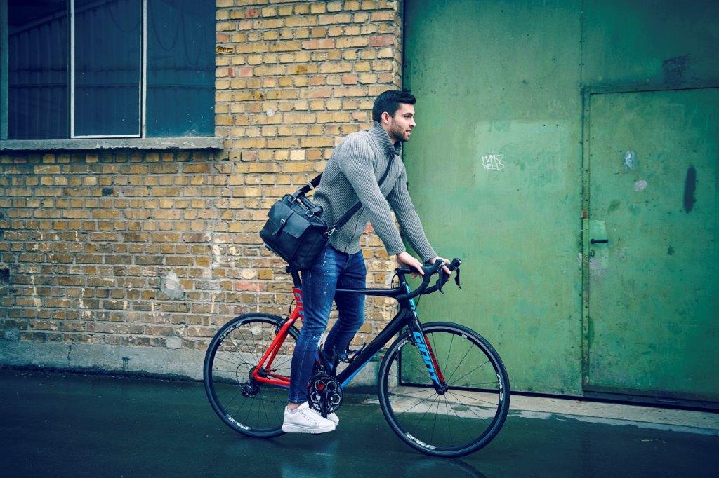 Ein Mann fährt mit einer Tasche auf dem Rücken Fahrrad.