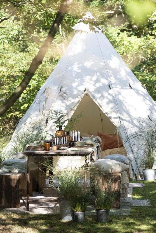 Ein weißes Tipi steht mitten auf einer Wiese.