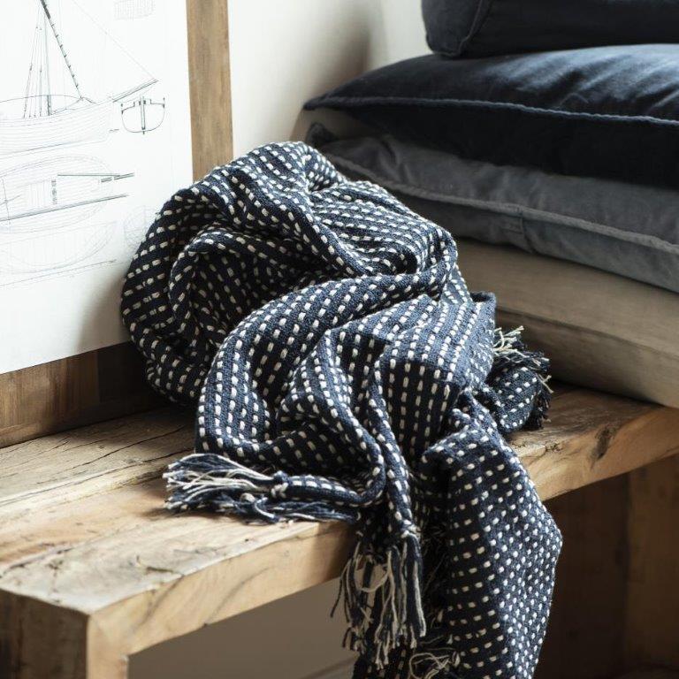 Eine blau-weiße Decke liegt auf einer Holzbank