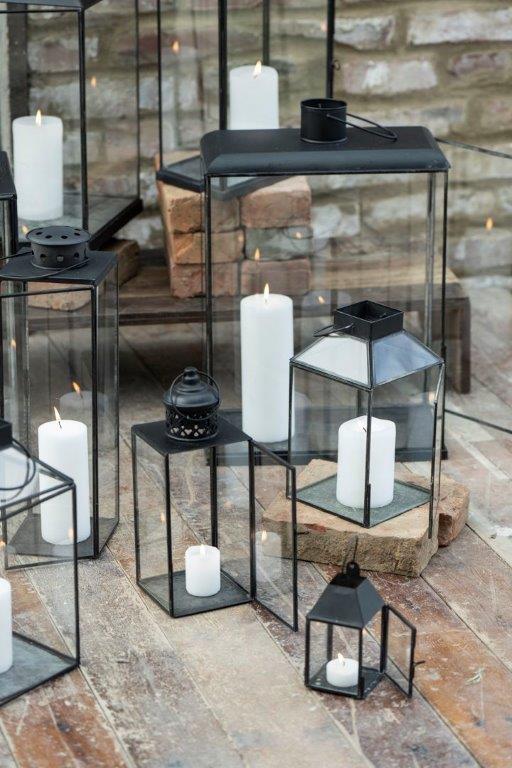 Auf einem Holzboden steht eine Gruppe von Laternen mit Kerzen darin.