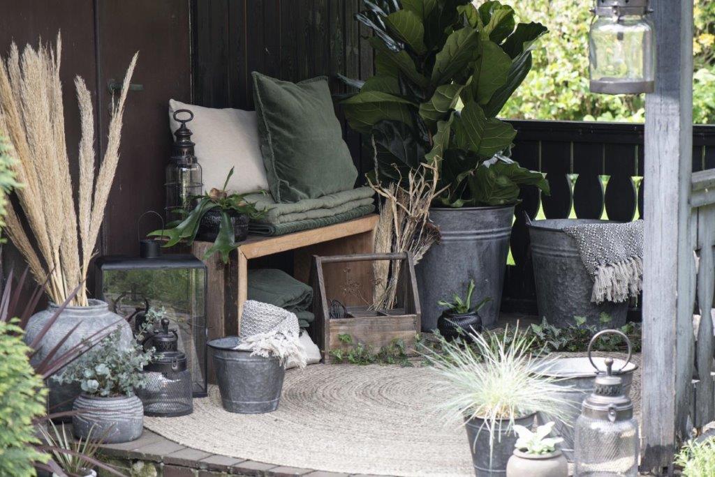 Eine Terrasse mit einer Bank, Topfpflanzen und Laternen.