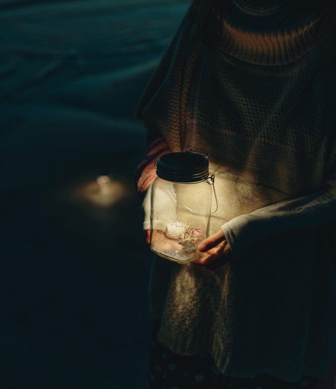 Eine Person hält im Dunkeln eine Laterne in den Händen.