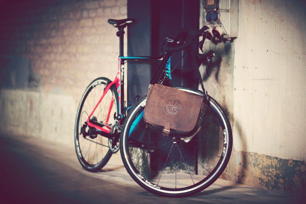 An einer Wand lehnt ein Fahrrad, an dem eine Tasche befestigt ist.