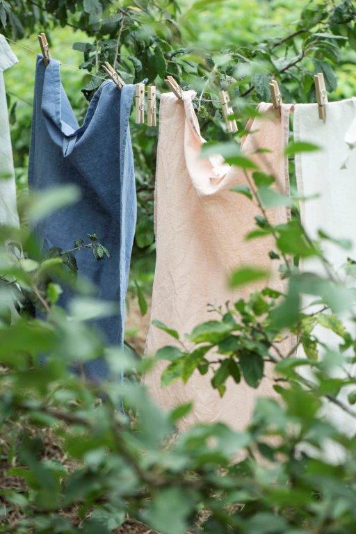 Eine Reihe Handtücher hängen auf einer Wäscheleine im Wald.