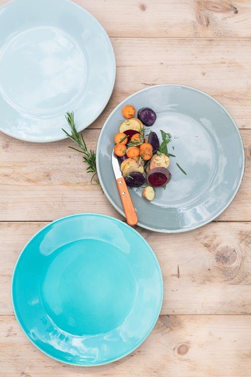 Auf einem Holztisch stehen drei Teller mit Gemüse.