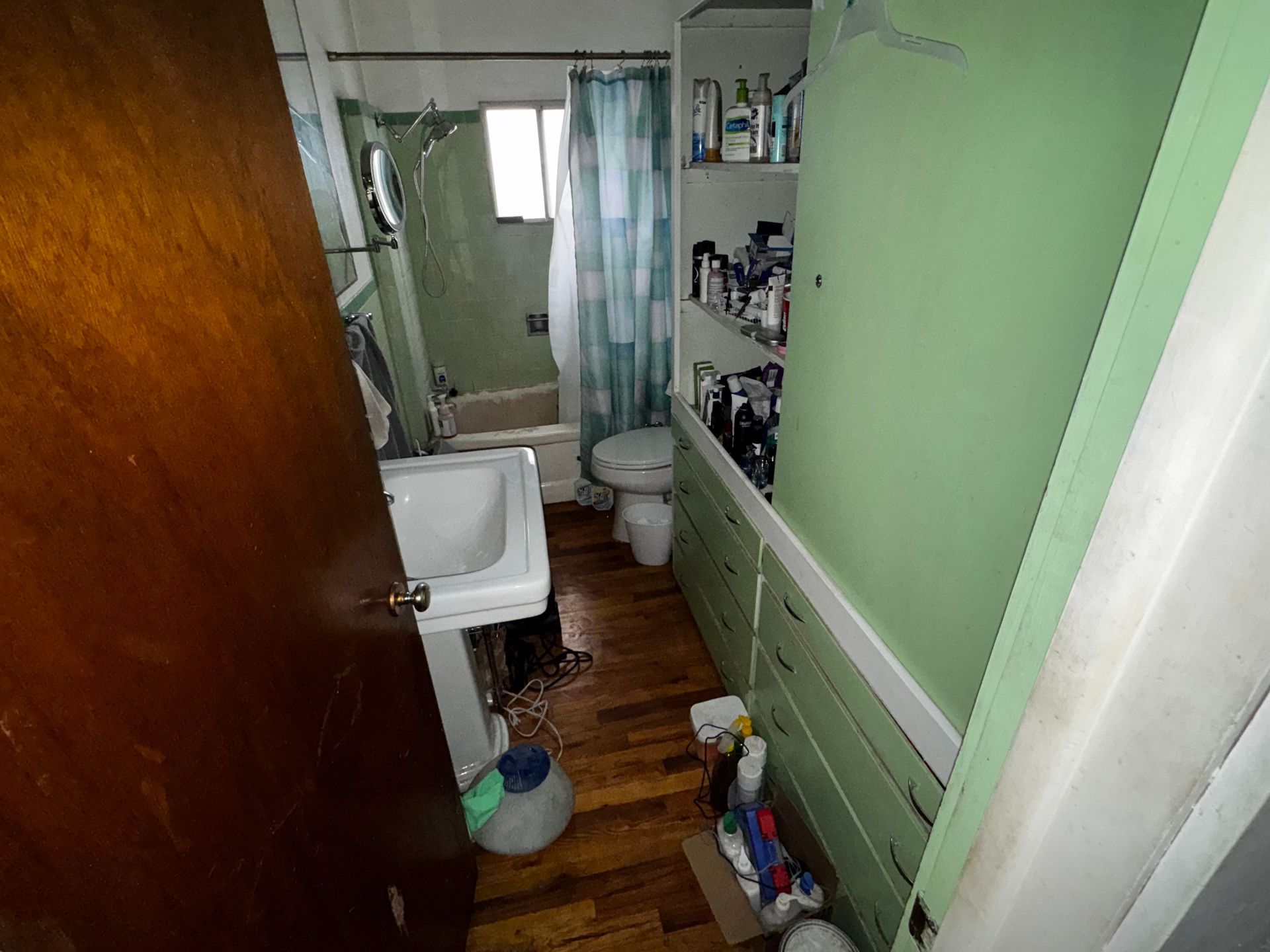 Dilapidated brown house with a destroyed wooden deck and overgrown weeds.
