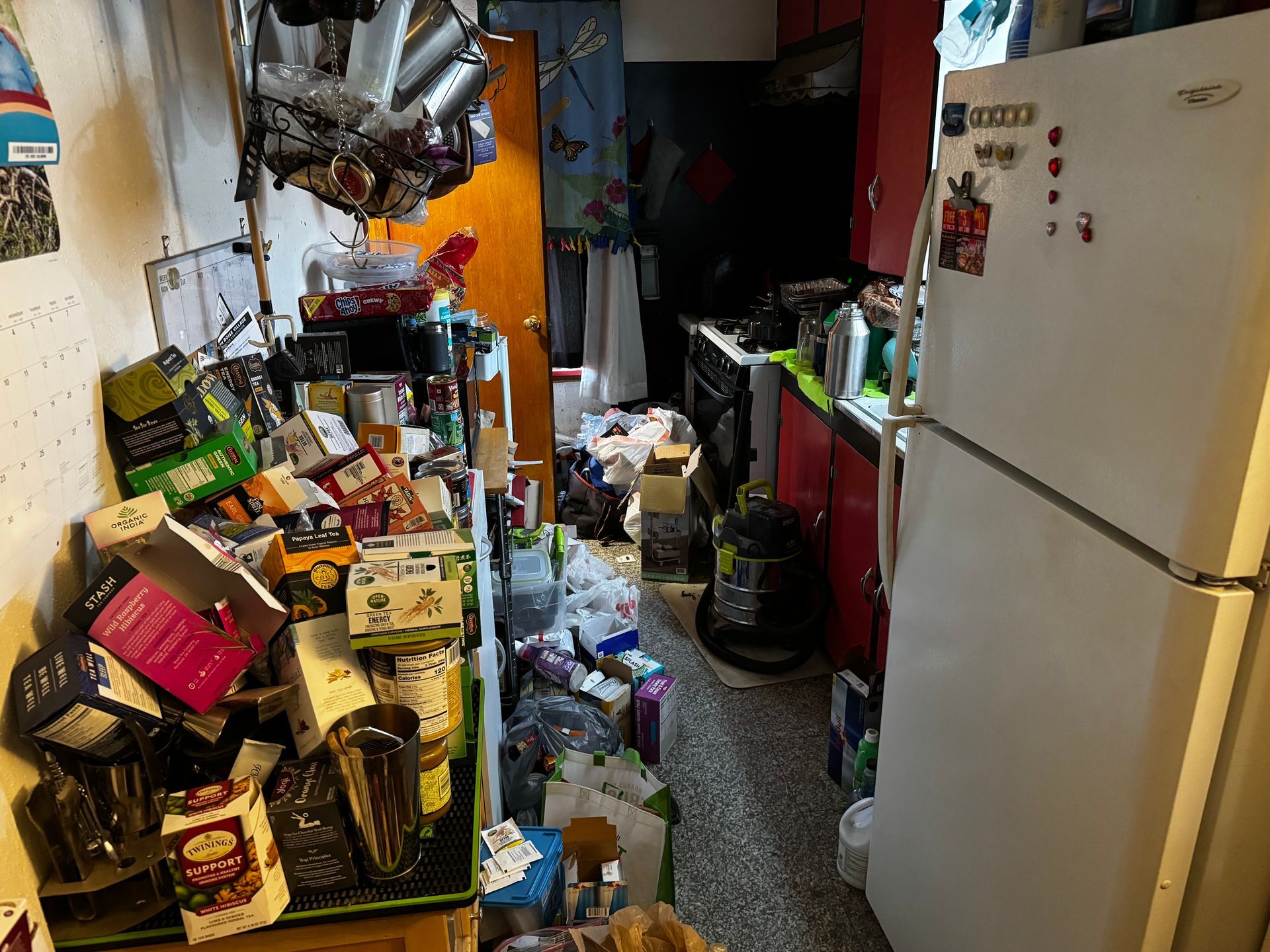 Dilapidated brown house with a destroyed wooden deck and overgrown weeds.