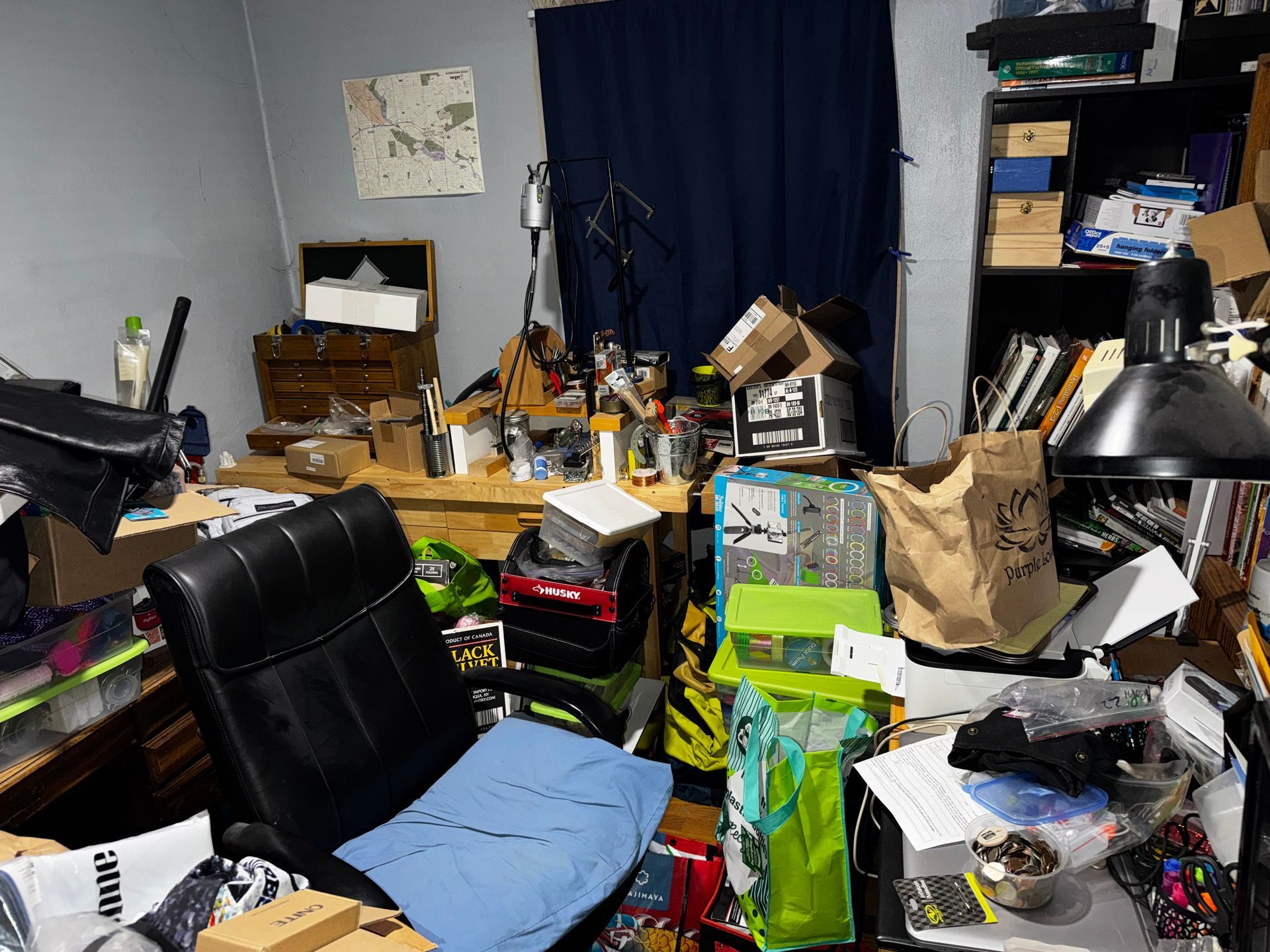 Brown, single-story house with a small loft and sliding glass door, set on a gravel field with trees in the background.