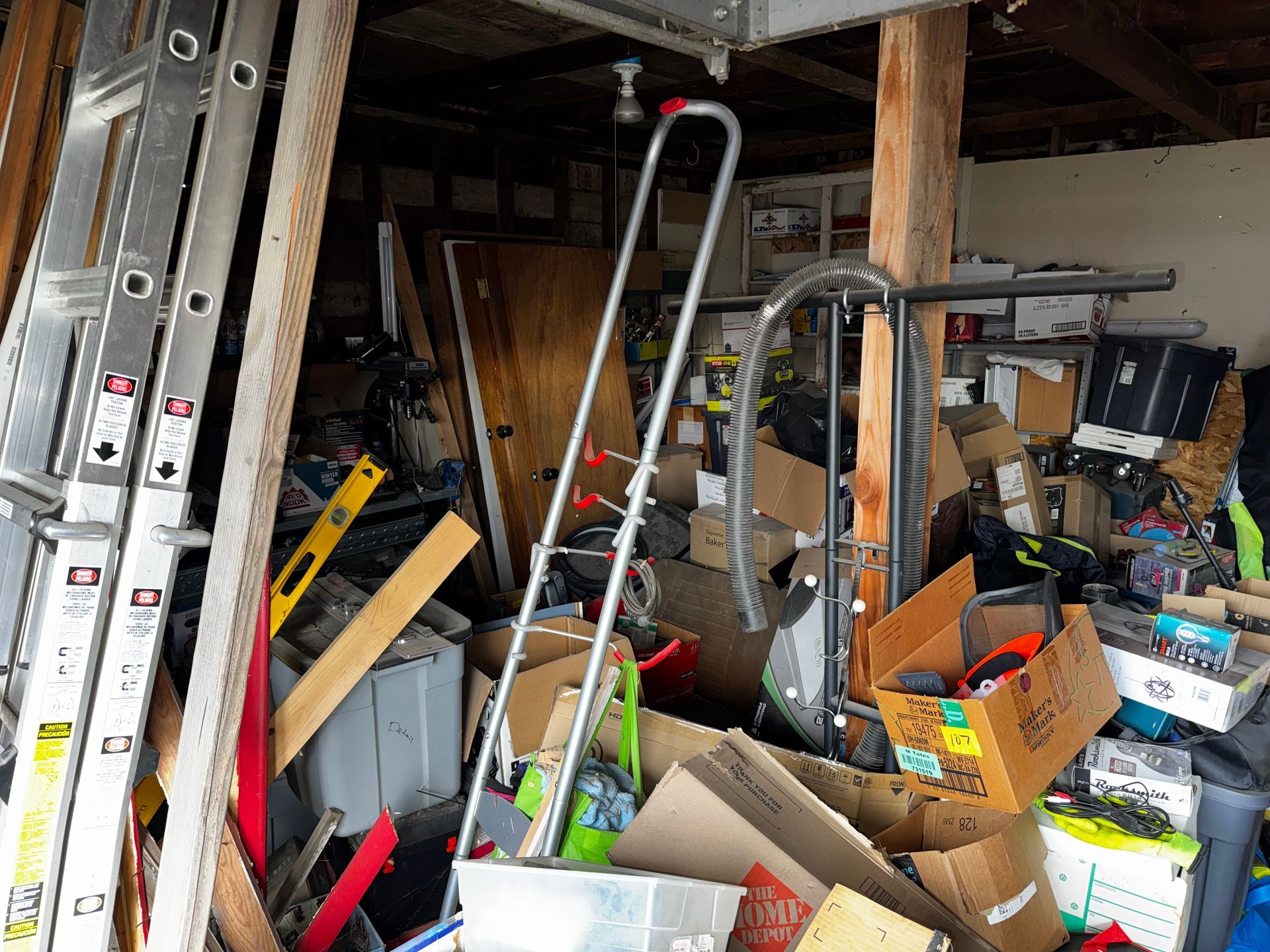 Brown, single-story house with a small loft and sliding glass door, set on a gravel field with trees in the background.