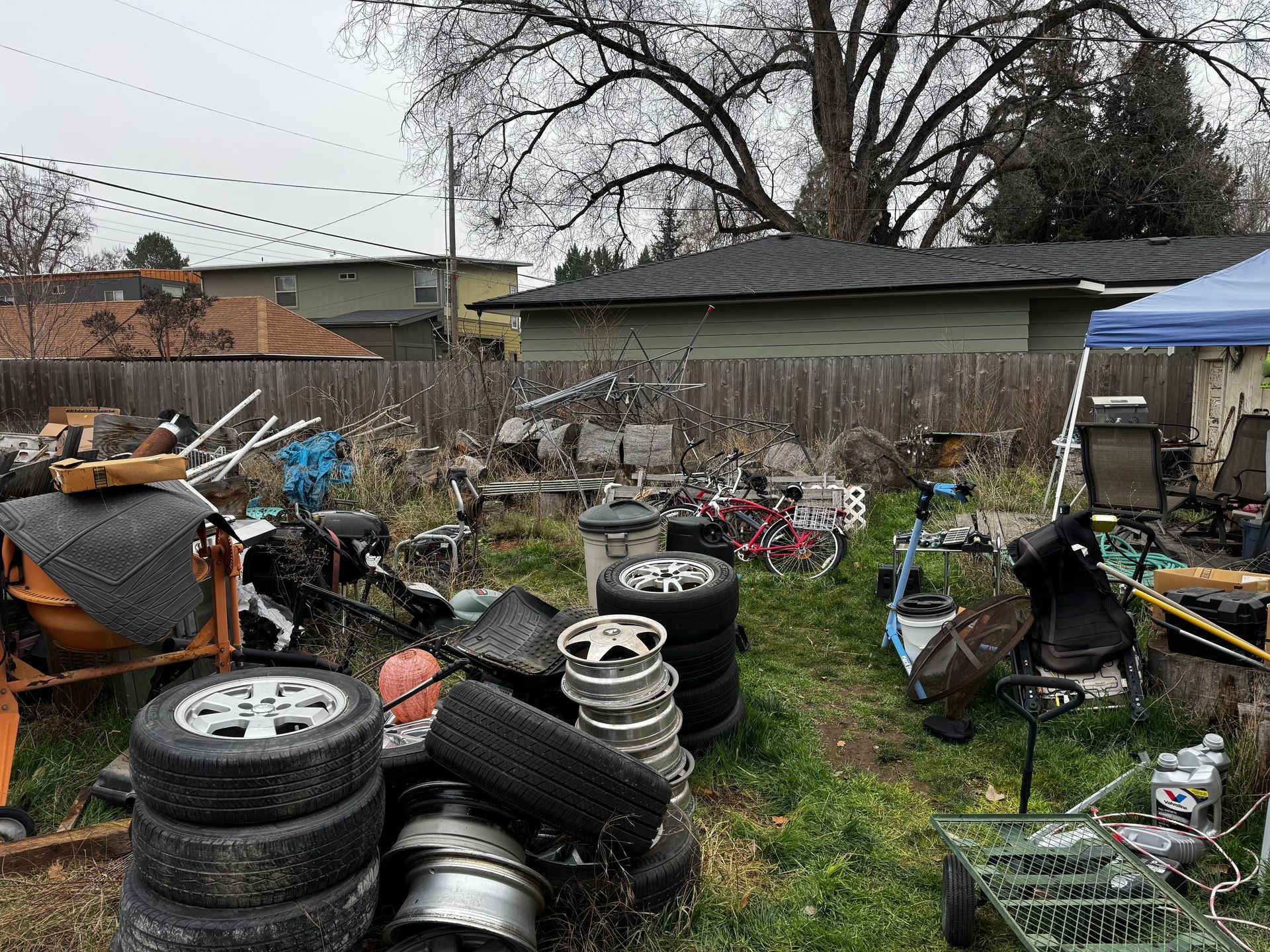 Dilapidated brown house with a destroyed wooden deck and overgrown weeds.