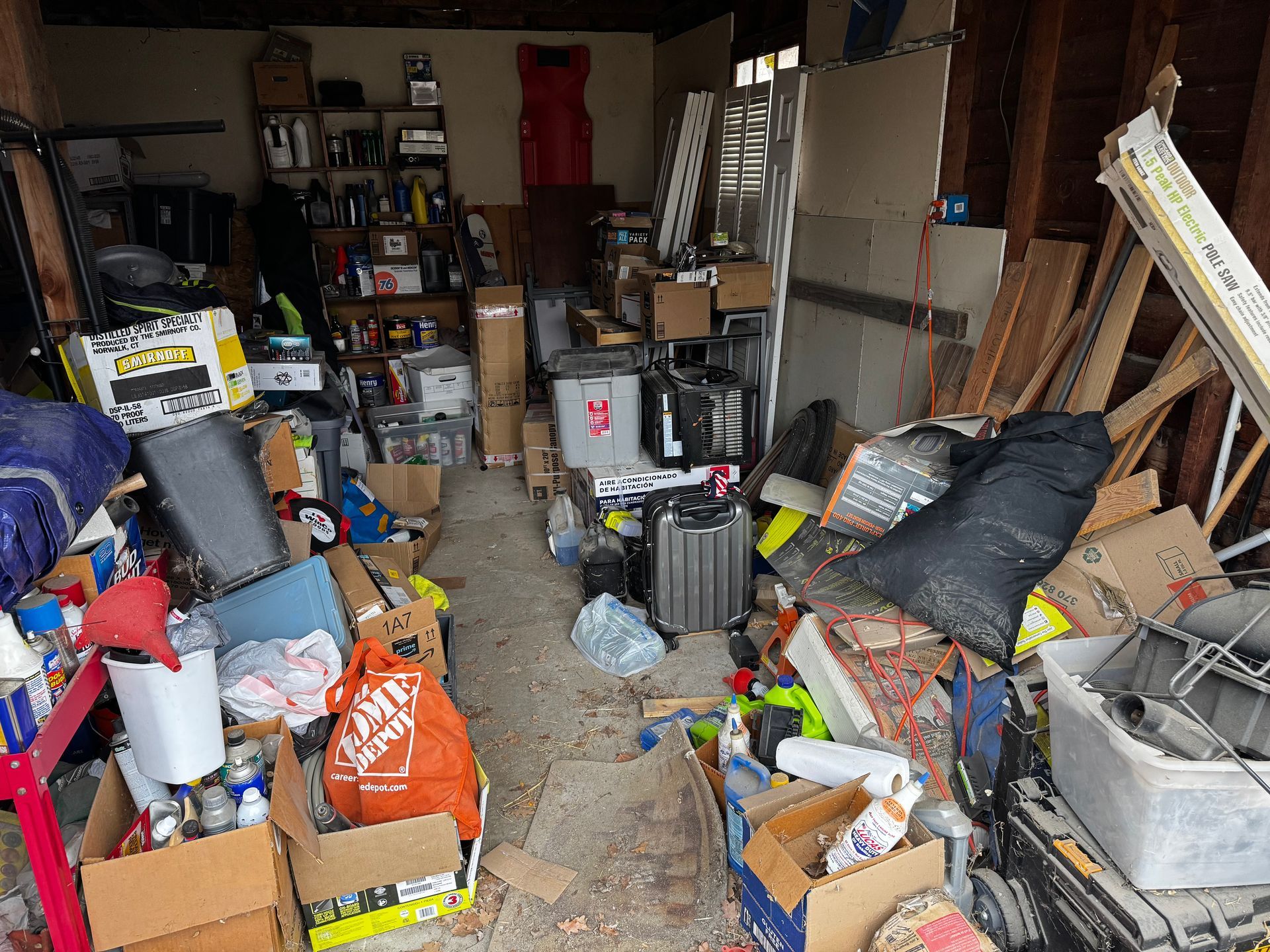 Brown, single-story house with a small loft and sliding glass door, set on a gravel field with trees in the background.