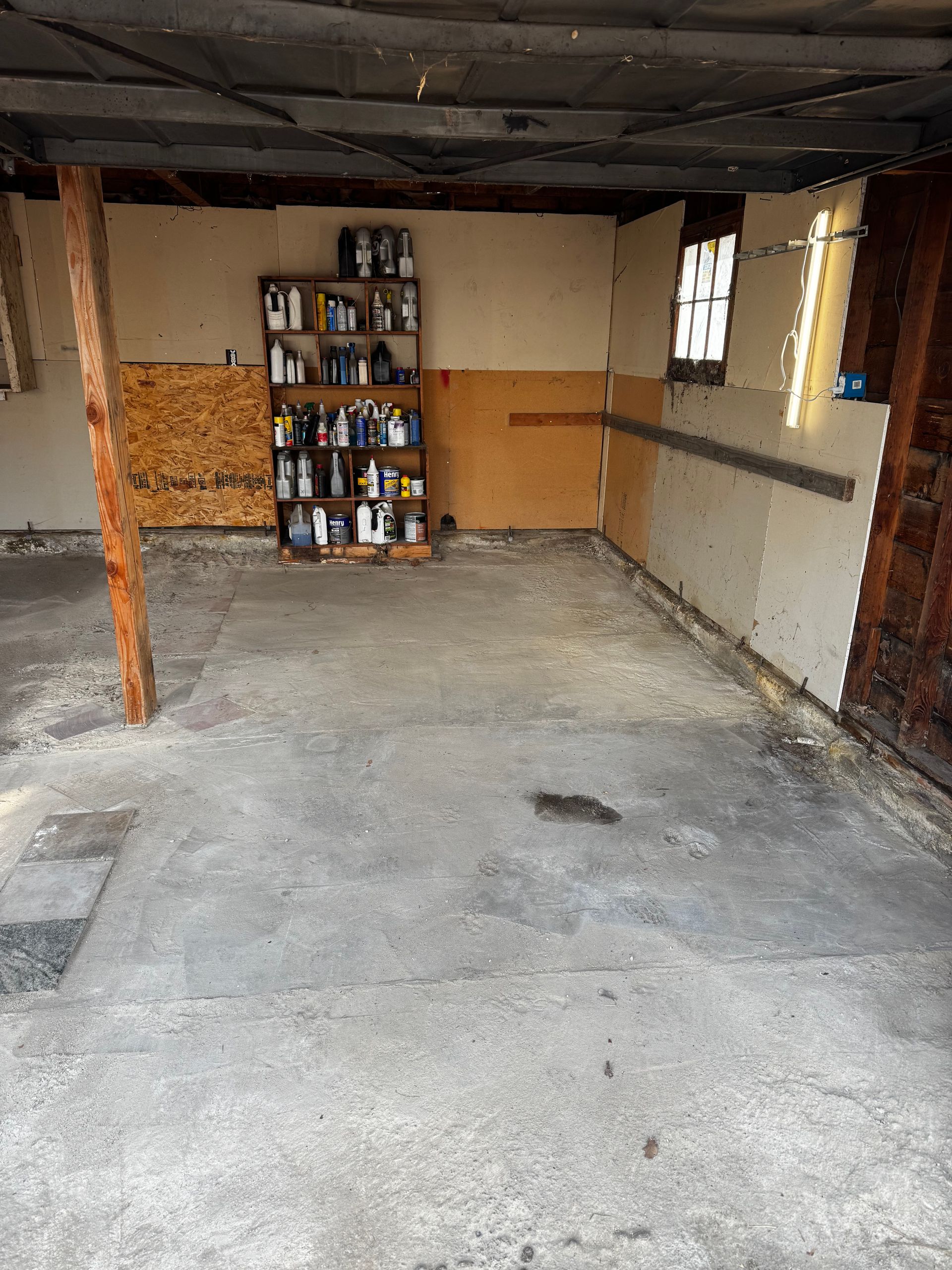 Wooden fence with two trash bins next to it on a concrete pad.