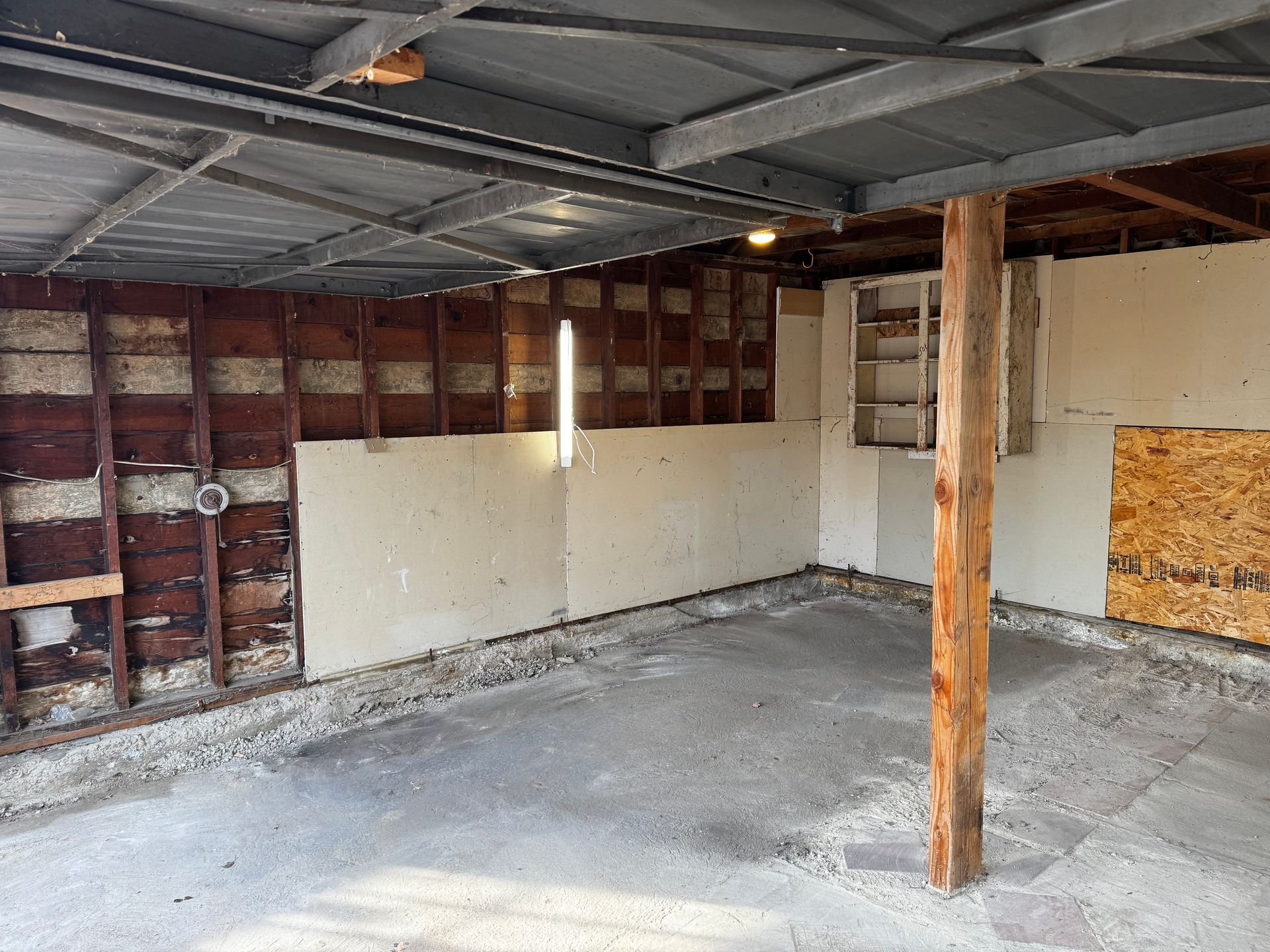 Wooden fence with two trash bins next to it on a concrete pad.